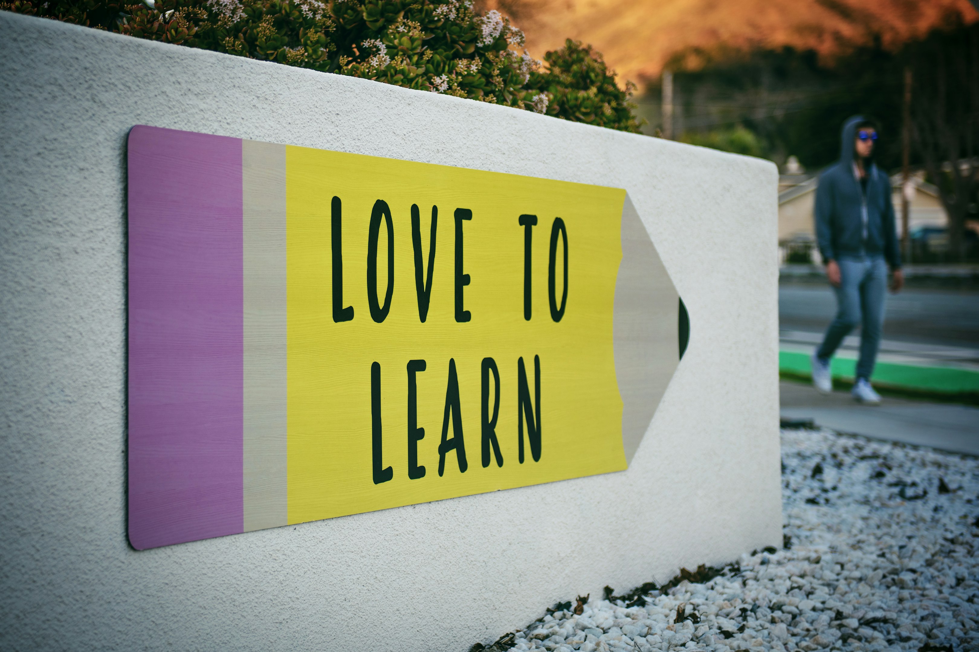 love to learn pencil signage on wall near walking man
