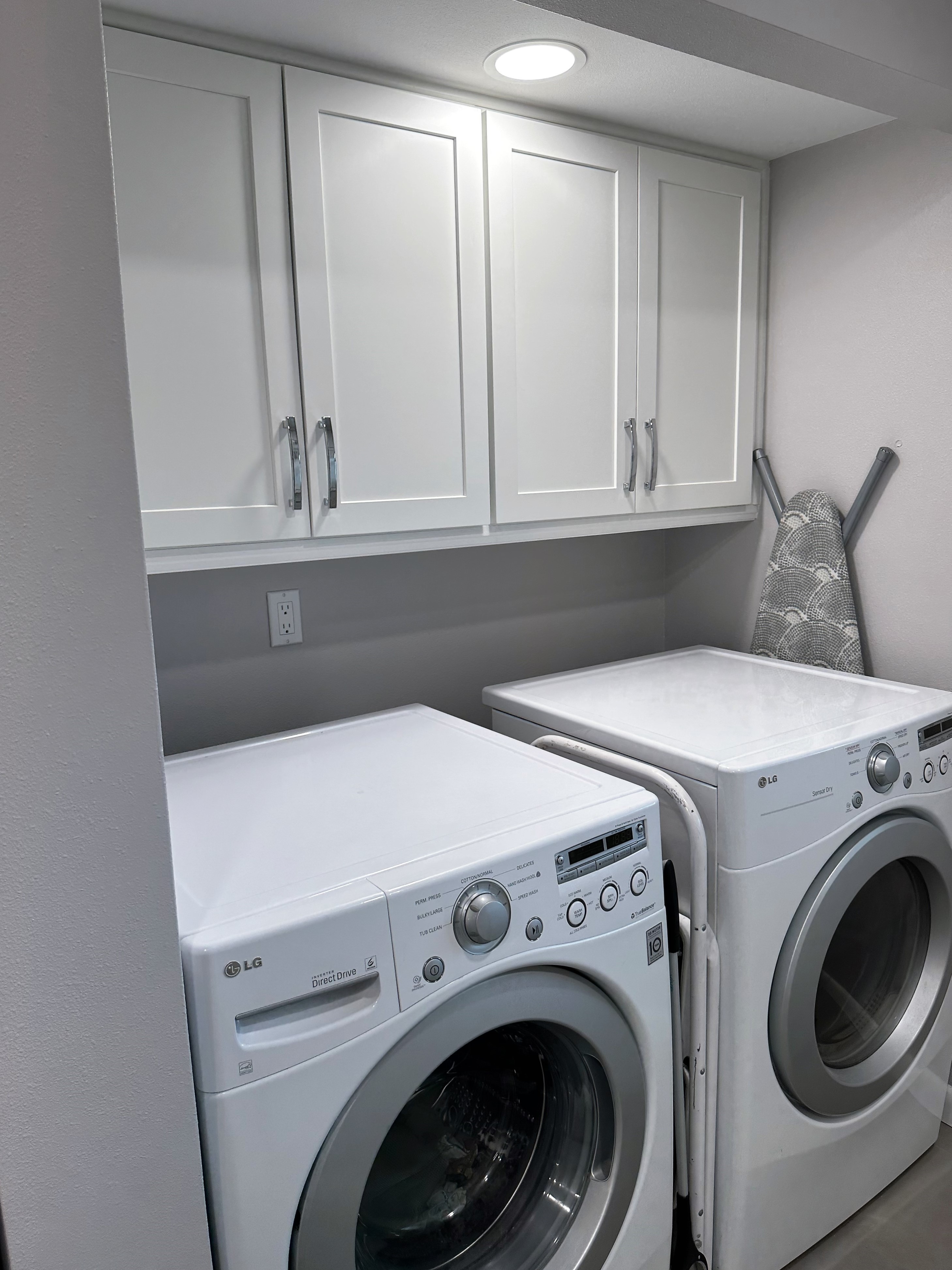 Laundry room just off kitchen featuring new white cabinetry, paint, and hardware.