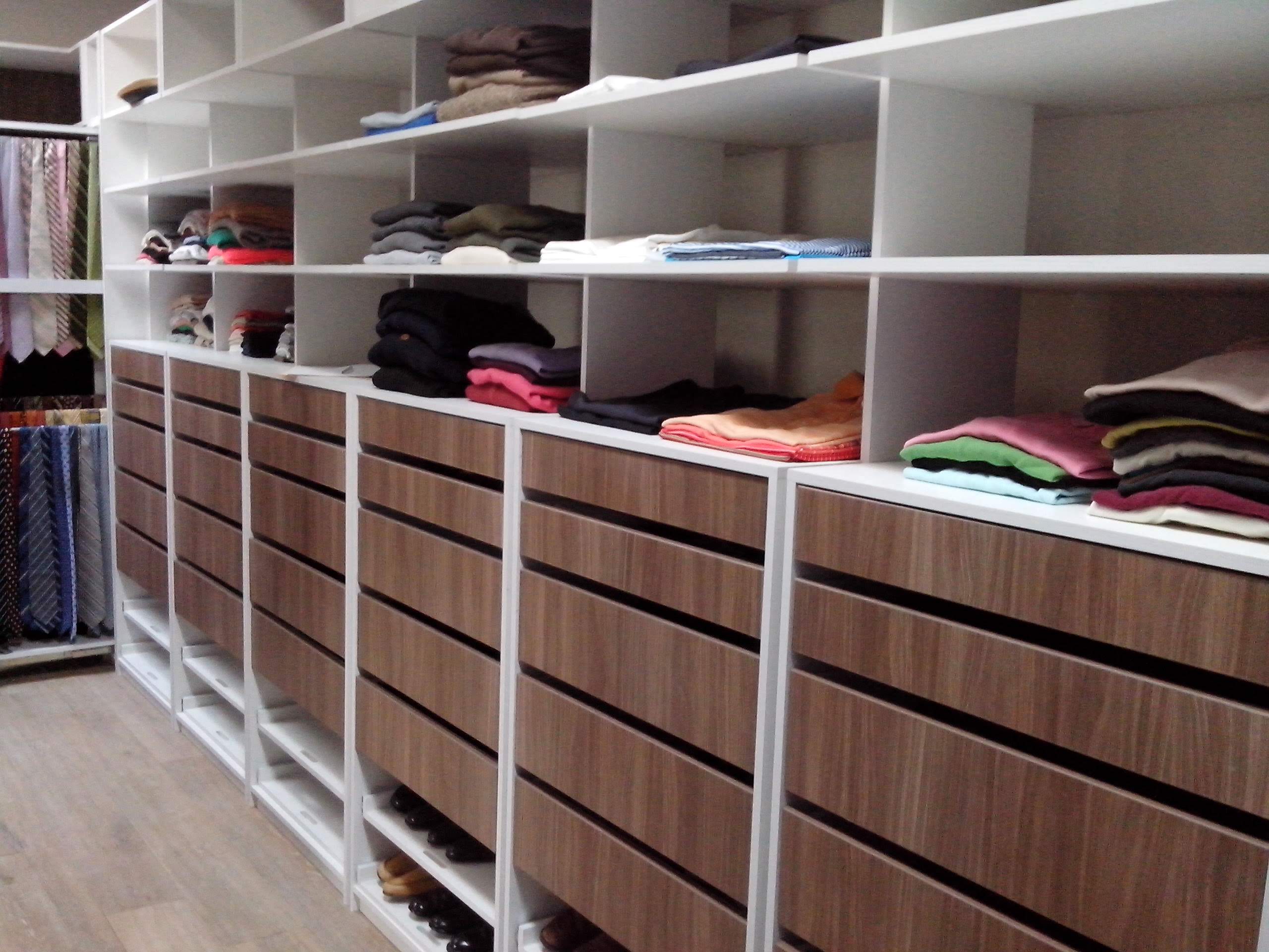 Cocina moderna con muebles de madera, encimera blanca, lámpara colgante negra y decoraciones de vidrio.
