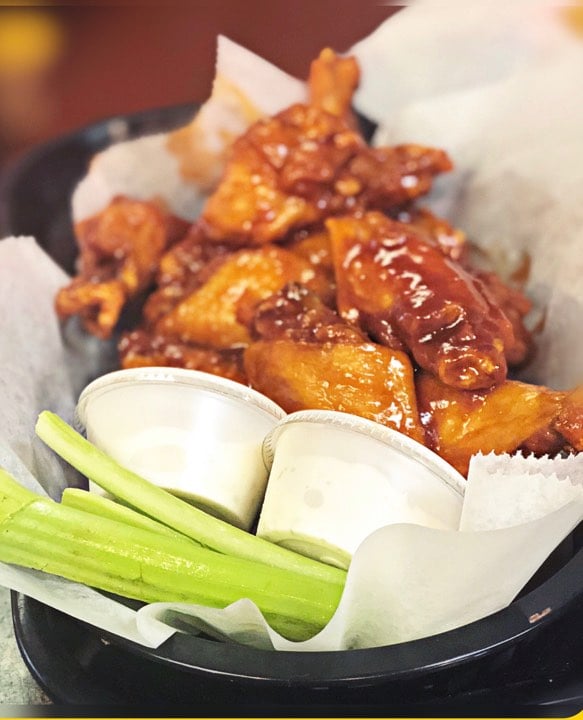 Buffalo chicken wings served with celery sticks and ranch dressing in a basket