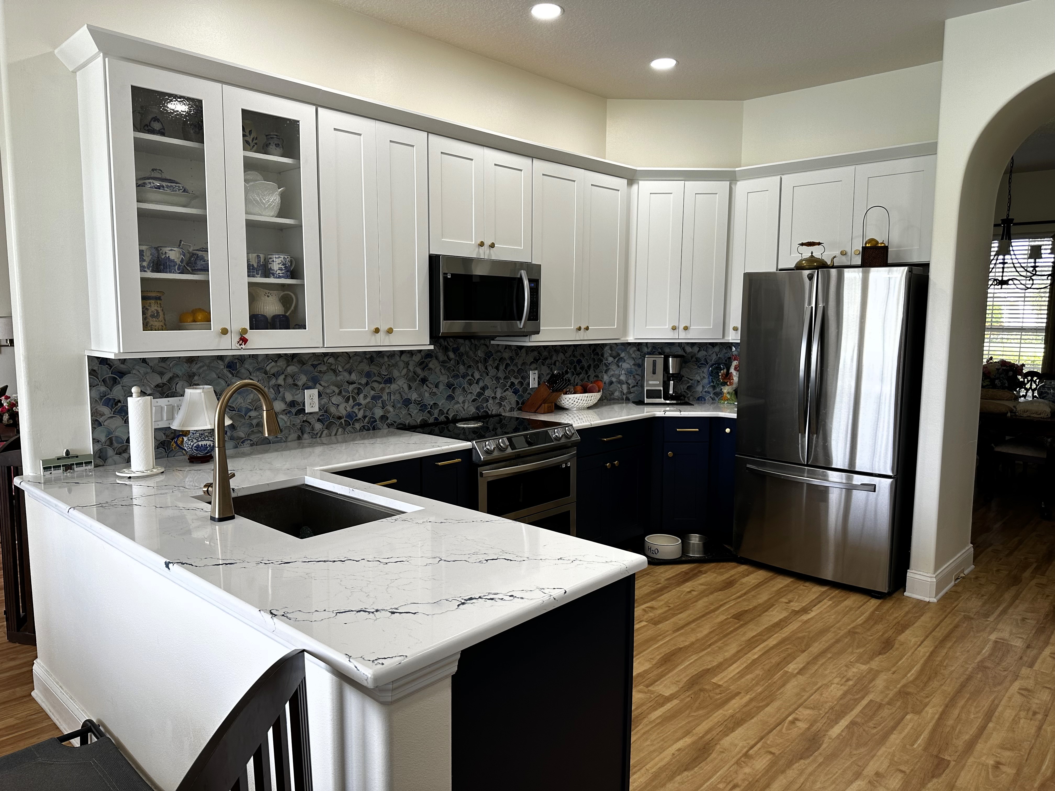 Charming kitchen featuring maple semi-custom cabinetry painted Naval (lowers) and White (uppers) while adding a touch of gold with the handles and knobs. 