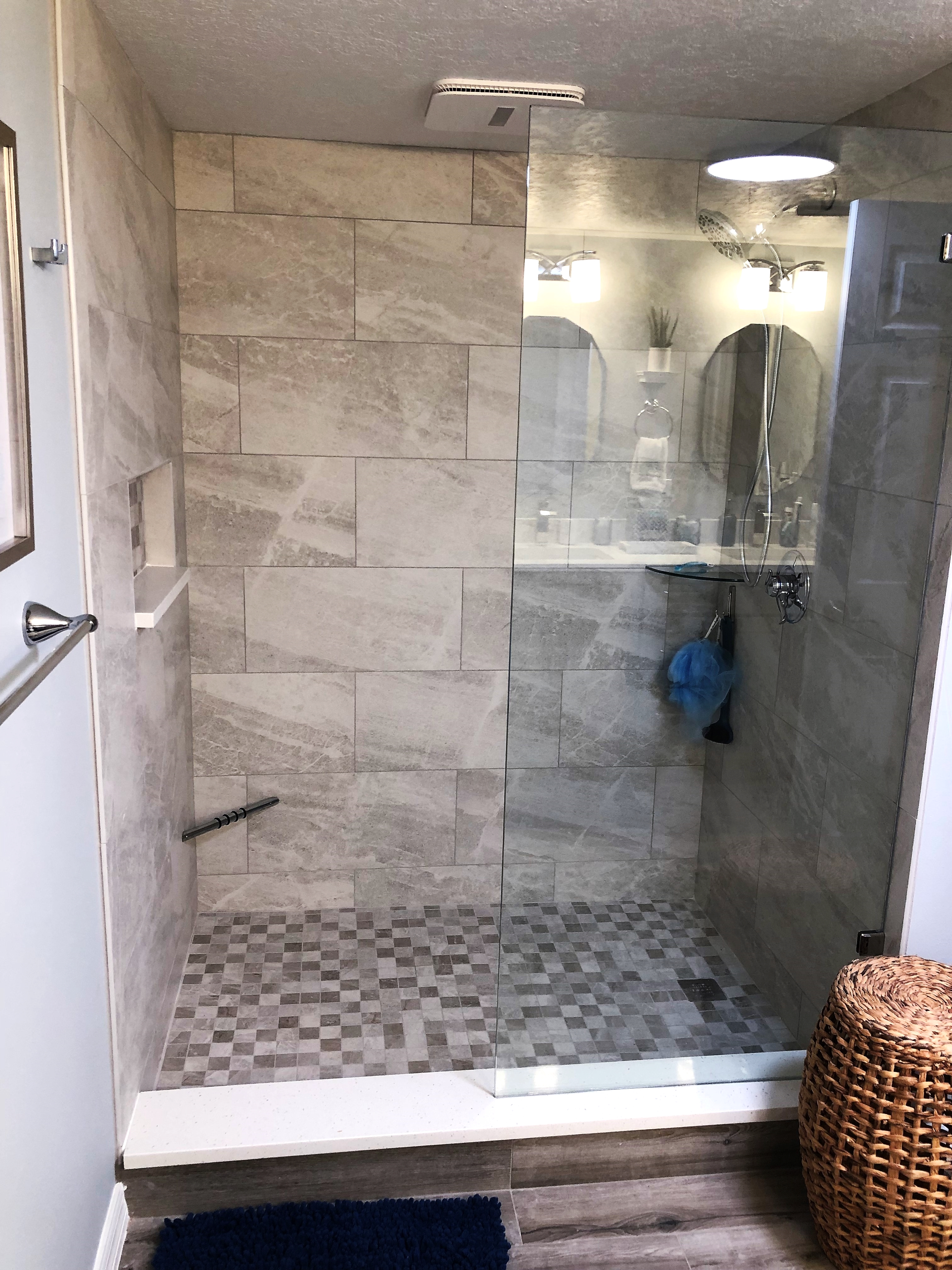 Porcelain tiled shower with niche, glass corner shelf, and heavy clear glass panel.