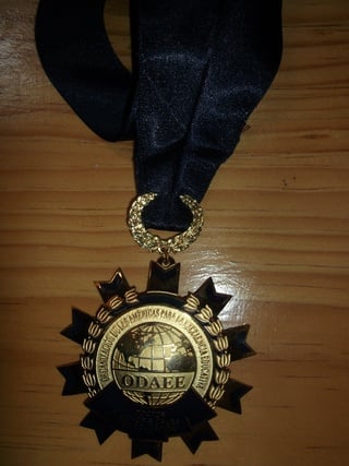 Gold and black ODAEE medal with ribbon on wooden surface