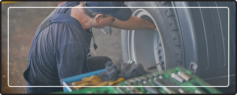 Close up of a man servicing a tire on a large truck.