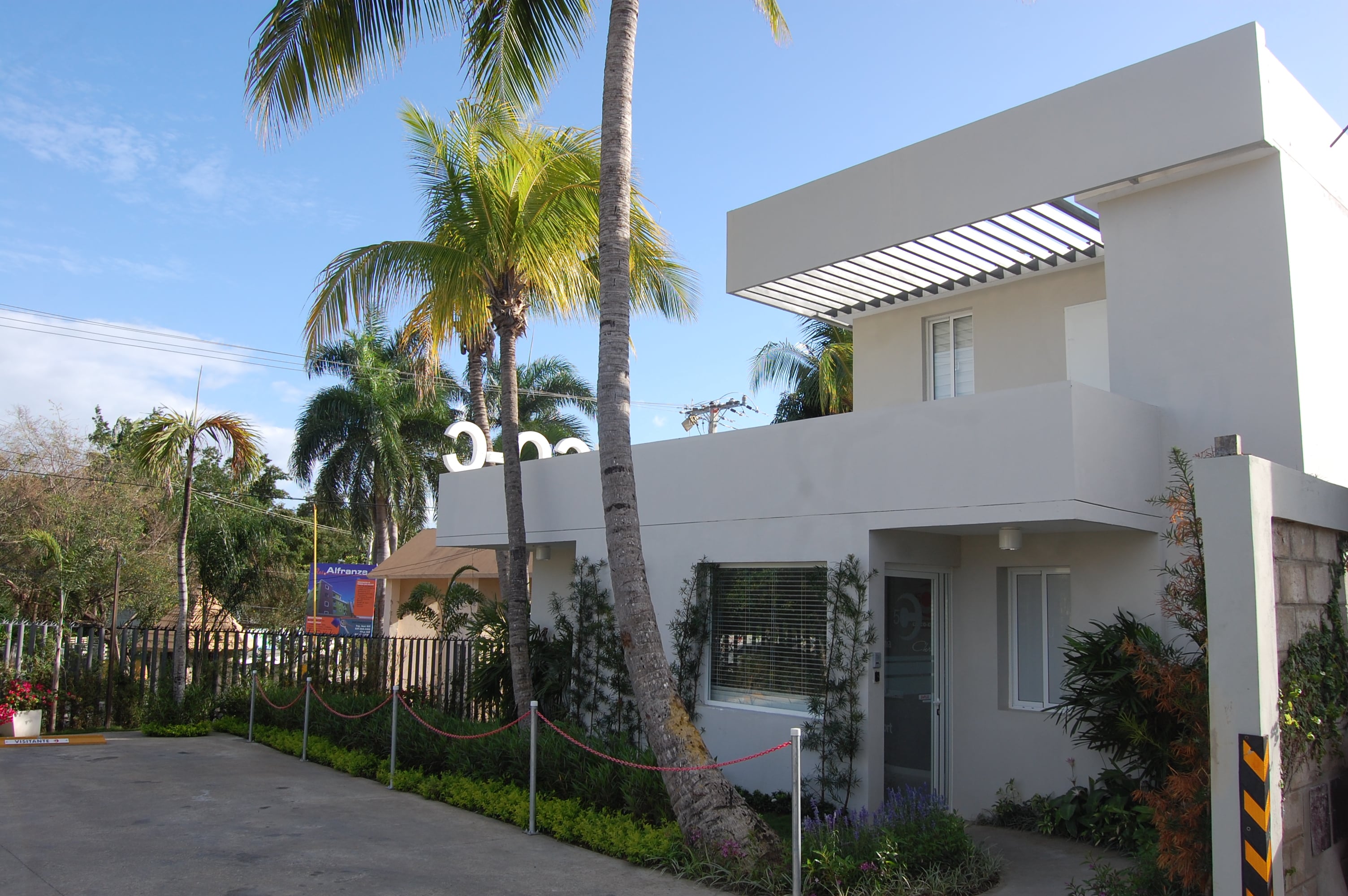 Edificio moderno blanco con palmeras tropicales y jardín en día soleado