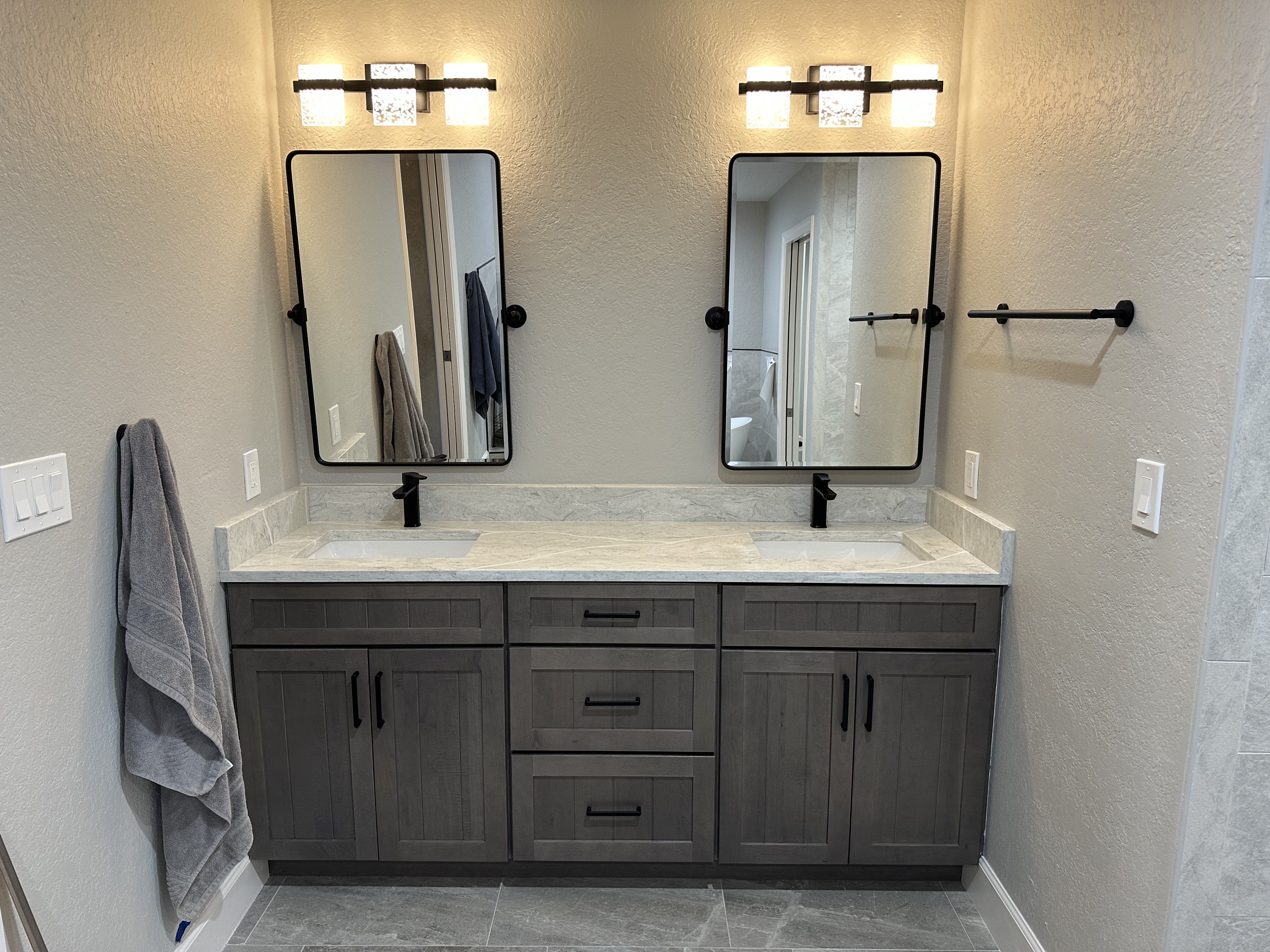 Perfect for two, this dual-sink vanity features mid-tone Dockside-stained cabinetry, matte black fixtures, and a
versatile Pompeii quartz countertop with a matching 4" backsplash—bringing both warmth and modern style to the space.