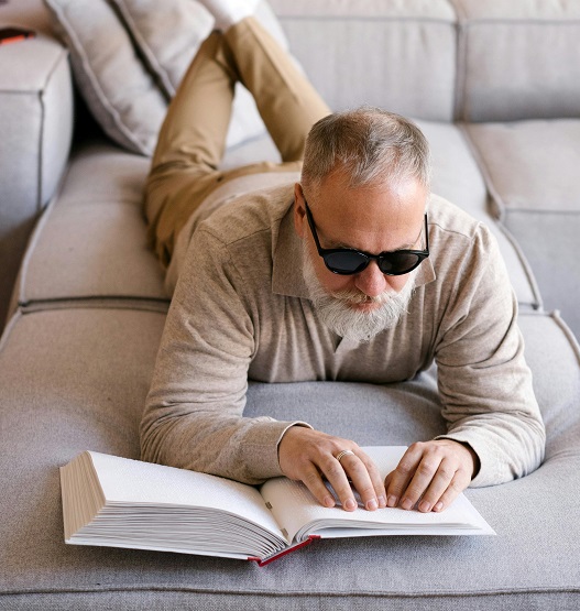 Man reading braille on a couch