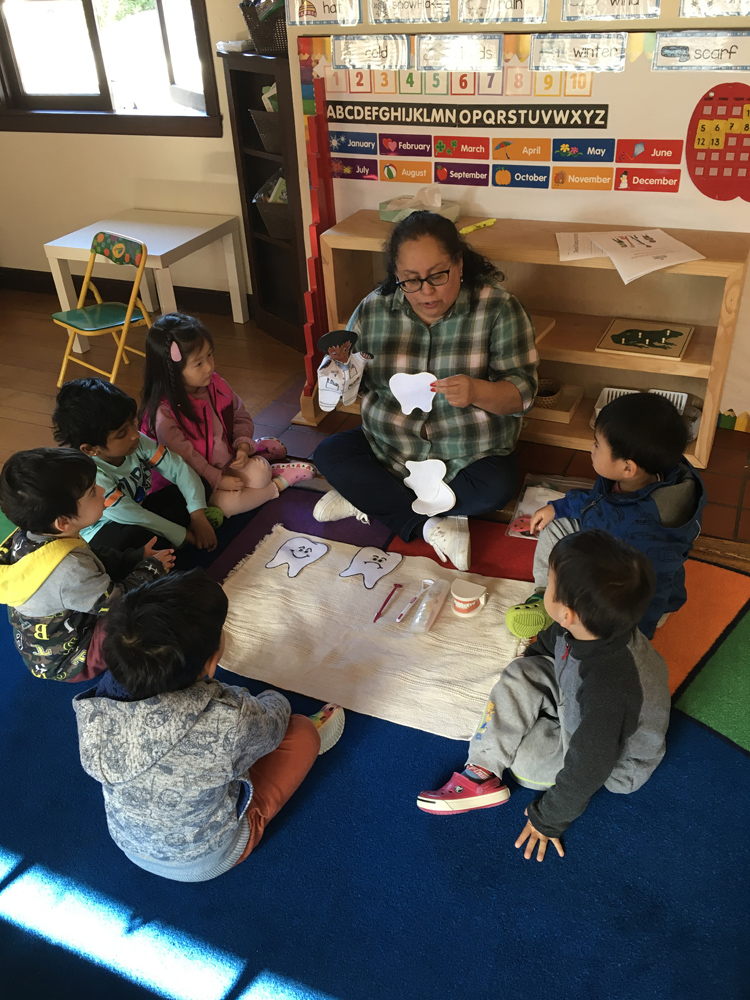 Students and a teacher playing with paper cutouts of teeth