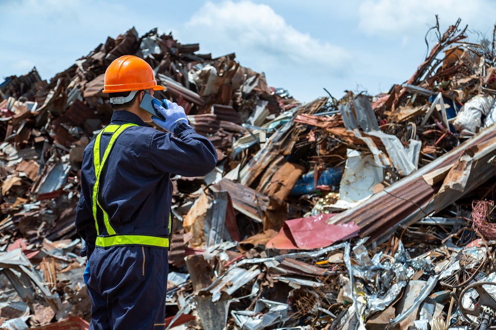 Worker in front of pile of scrap metal Worker in front of pile of scrap metal