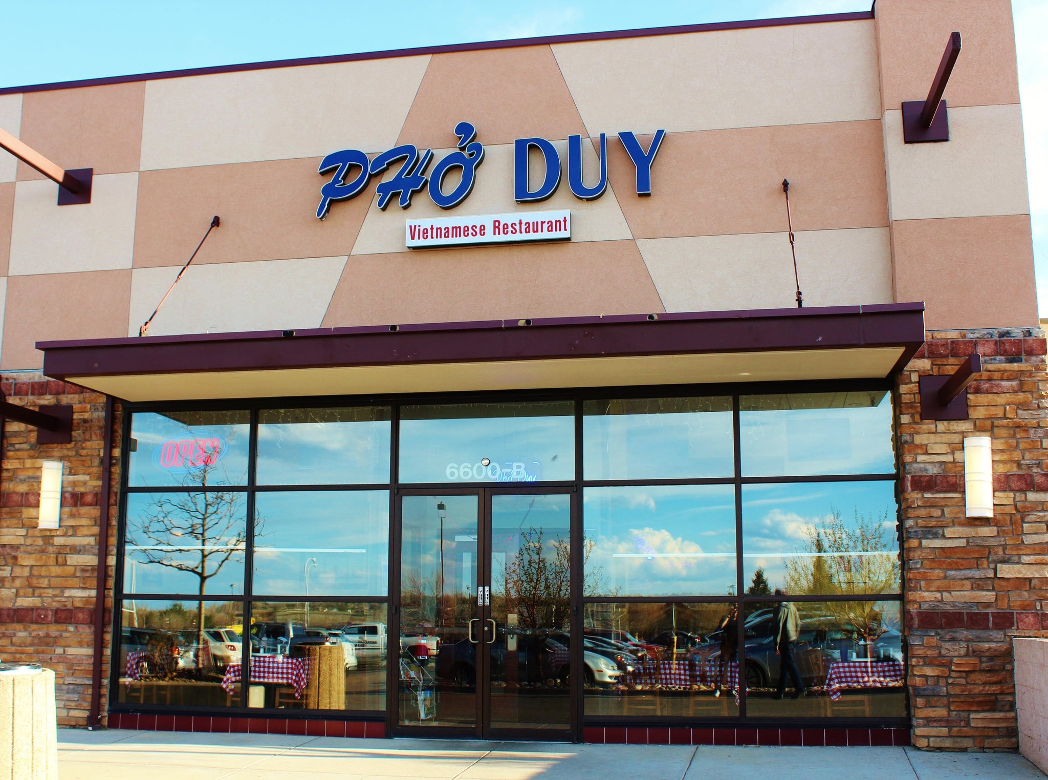 Front view of a Vietnamese restaurant named Pho Duy with large windows and a brick exterior.