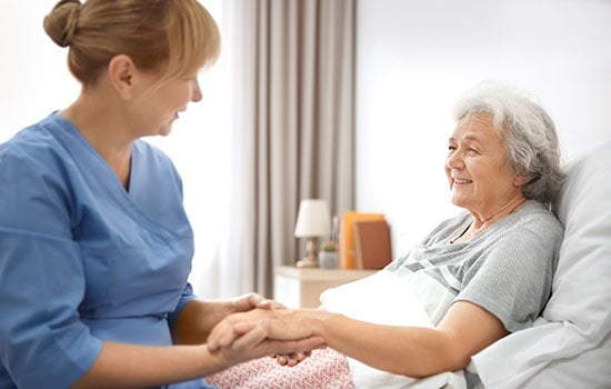 Caregiver Massaging Hand Of Senior Woman At Home