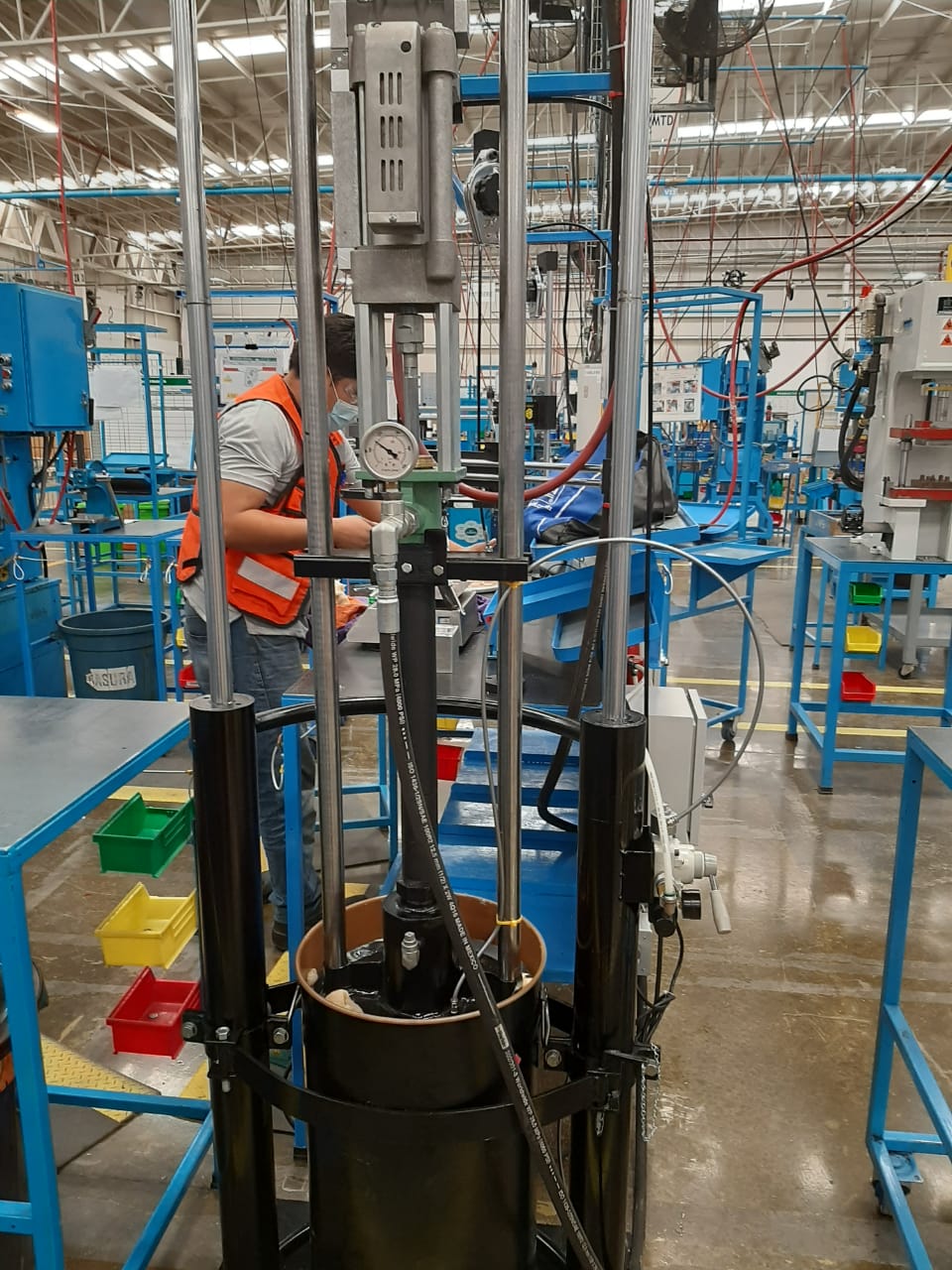 Técnico operando equipo hidráulico industrial con manómetro en línea de producción de fábrica
