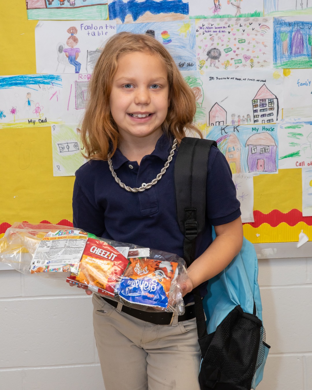 Children and adults playing tug-of-war at a sunny outdoor event with tents and trees in the background.