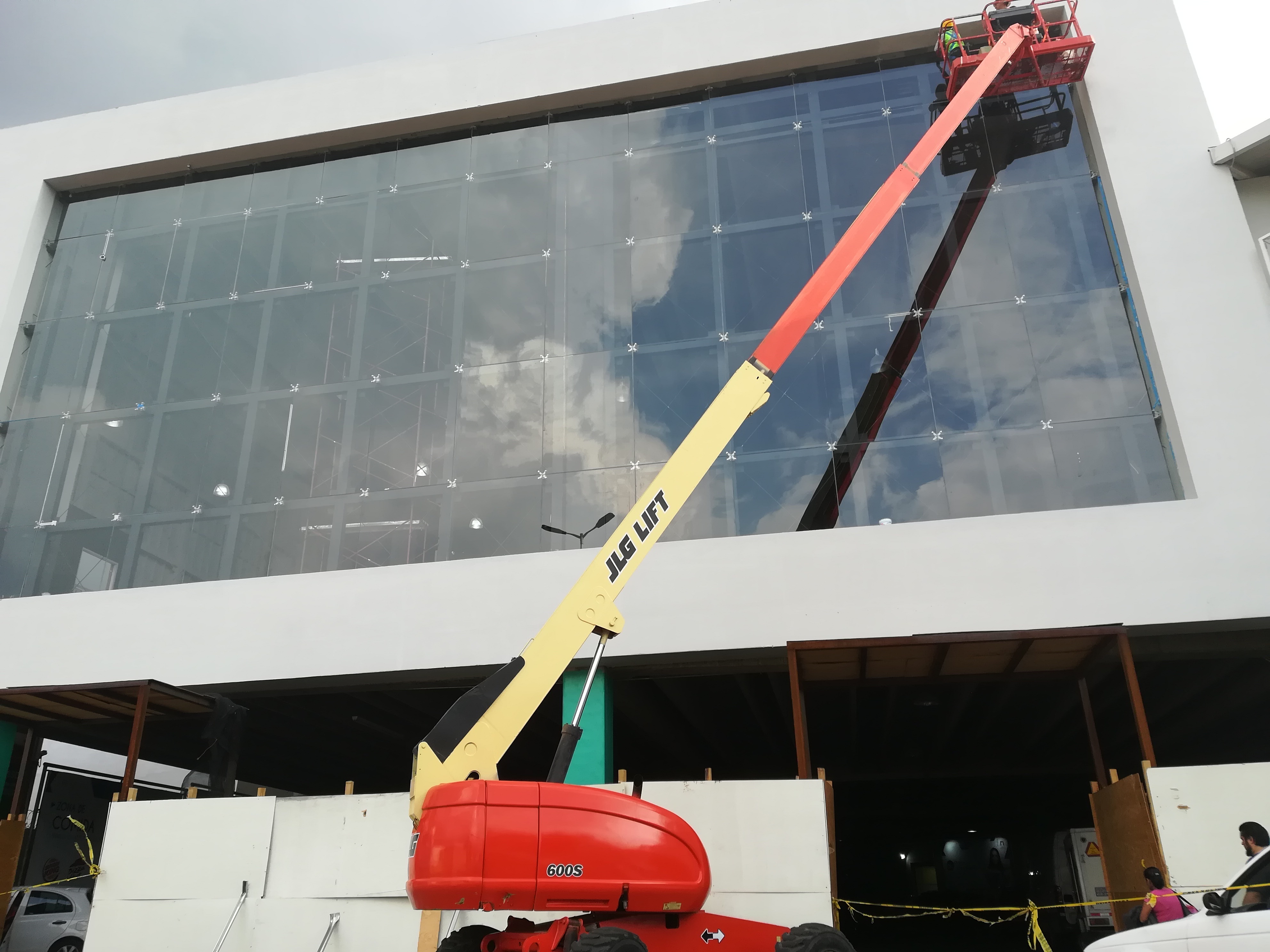 Personal trabajando en una plataforma para la colocación de fachada de vidrio en Plaza Coacalco.