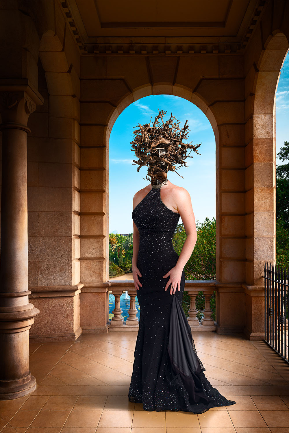 Surreal image of woman with a head of leafless vine branches, dressed in a formal gown, standing on a palace’s classical portico.