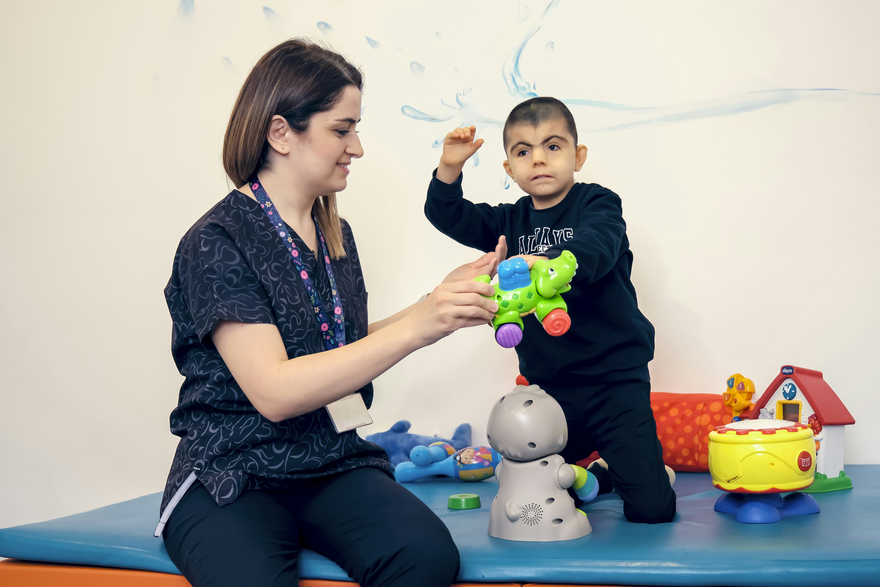 Terapeuta infantil jugando con un niño en sala de terapia con juguetes educativos
