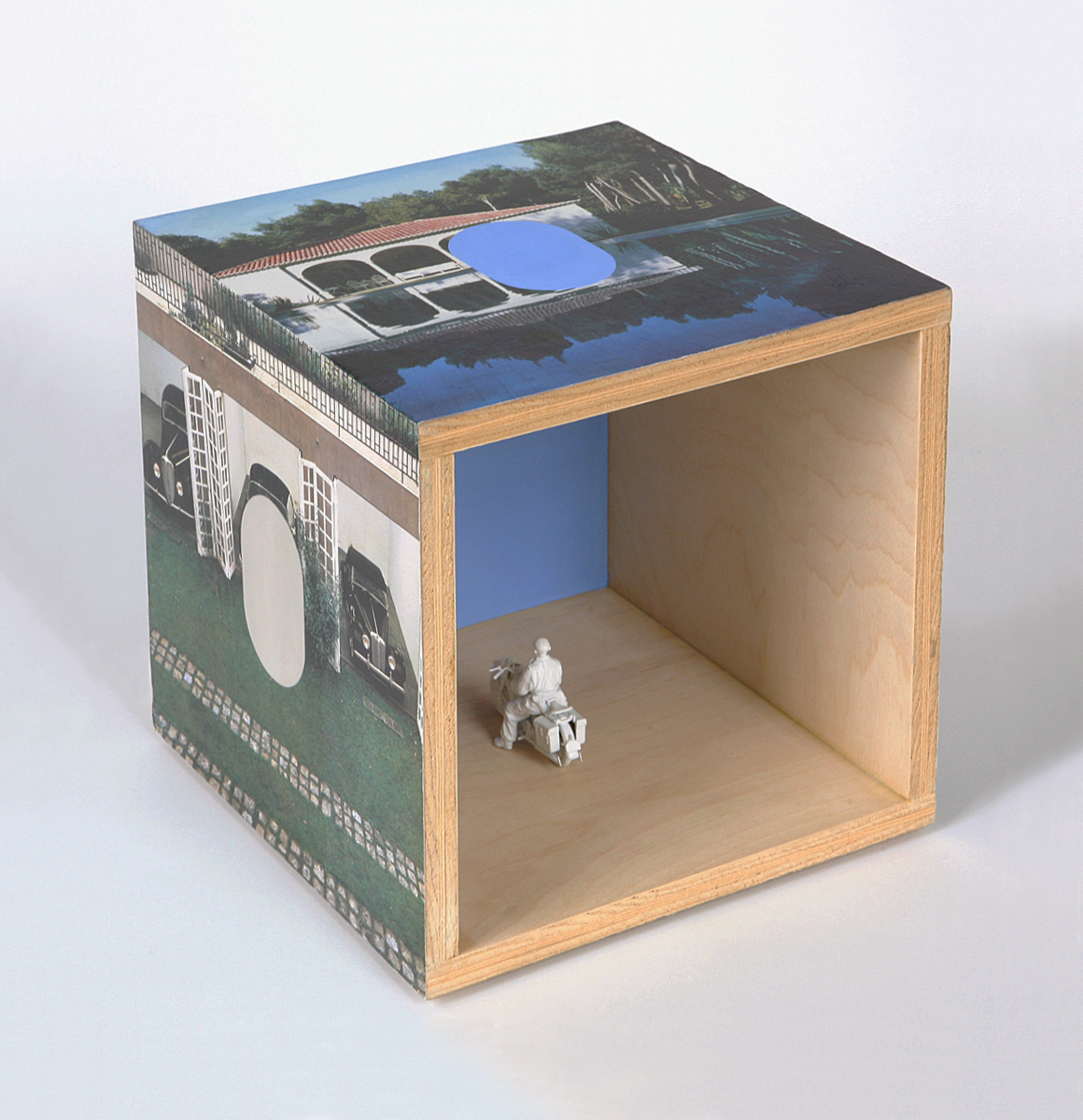 A plywood cube with imagery on the outside and a motorcycle model inside.