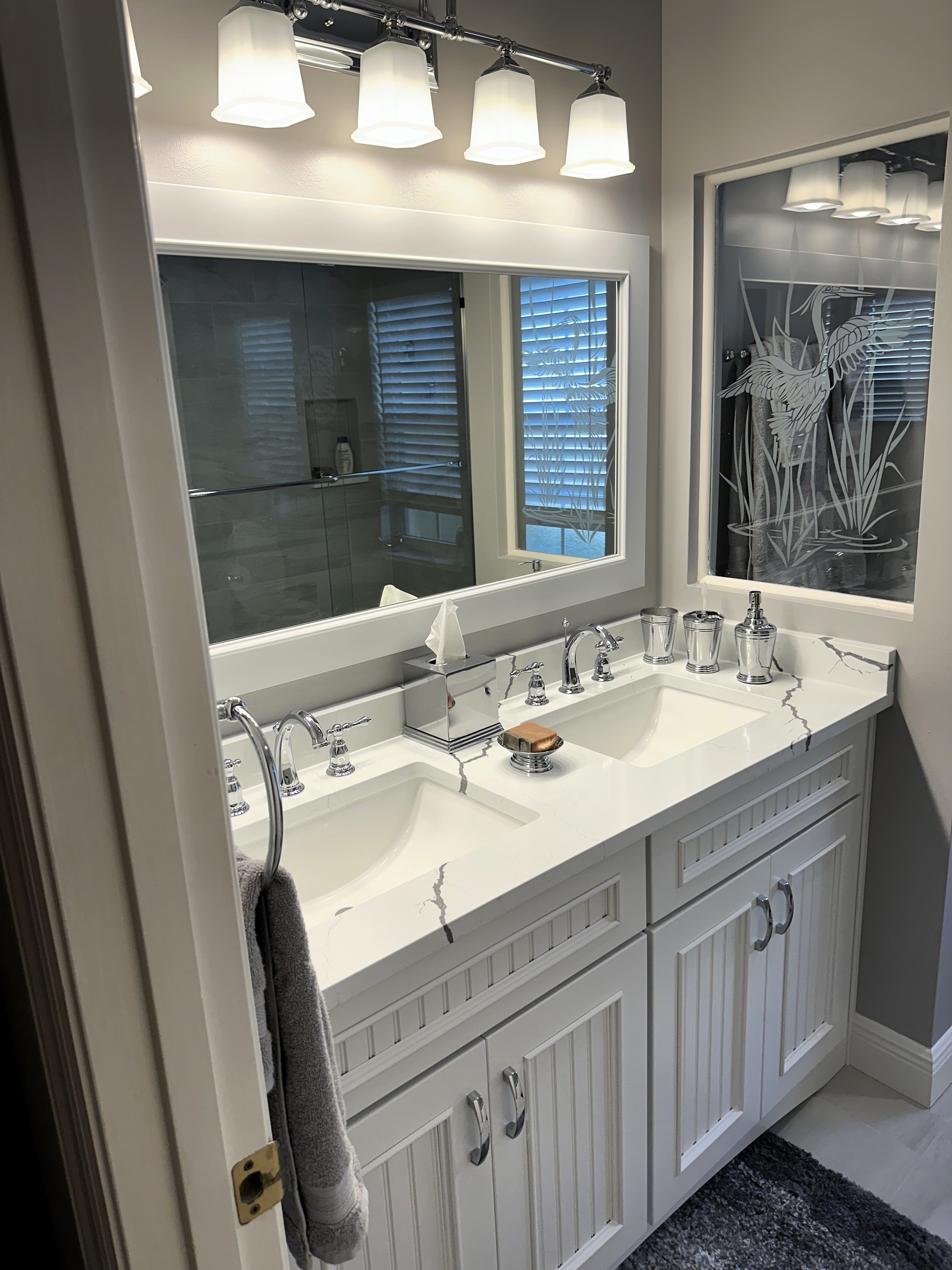 Perfect vanity for two featuring semi-custom painted maple wood cabinetry with Pompeii quartz countertop and matching 4" backsplash.  The chrome fixtures and handles make this vanity pop.