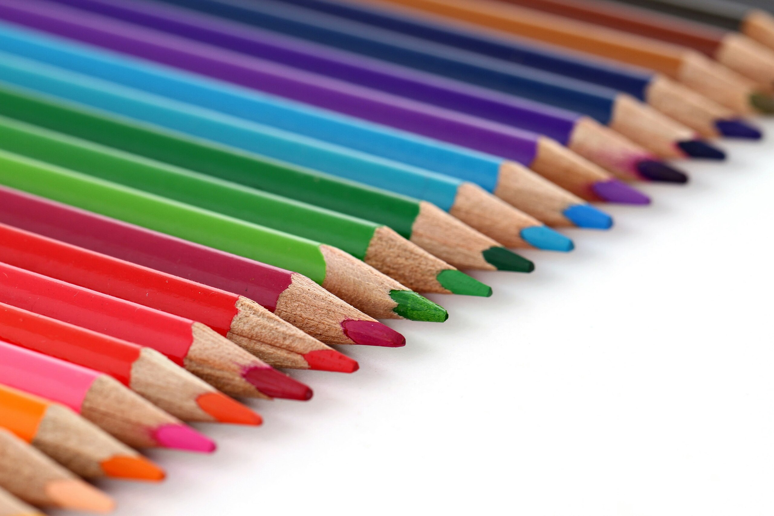 Lápices de colores alineados sobre una superficie blanca, mostrando una amplia gama de tonos vibrantes.