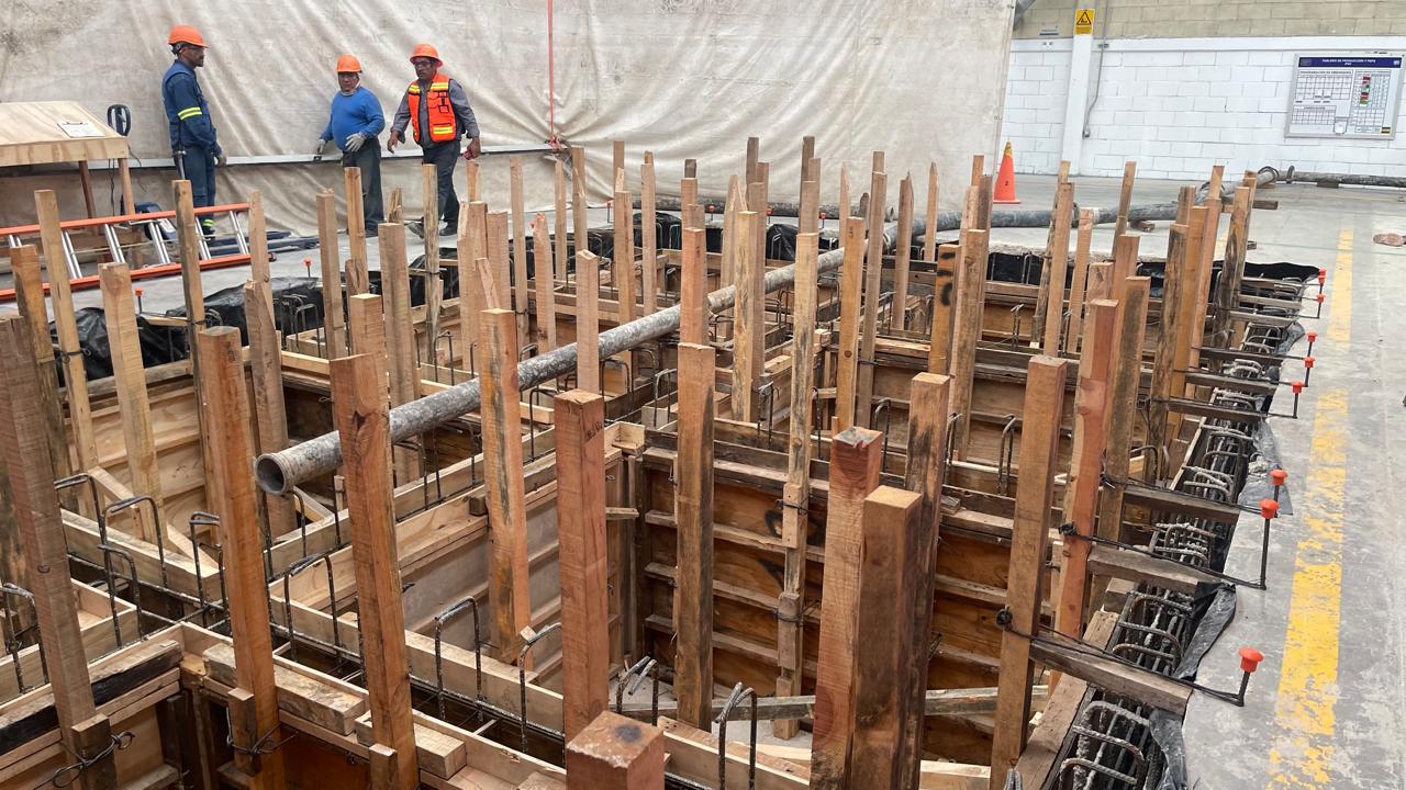 Espaciosa área común en edificio moderno con sofás naranjas y ventanas grandes.