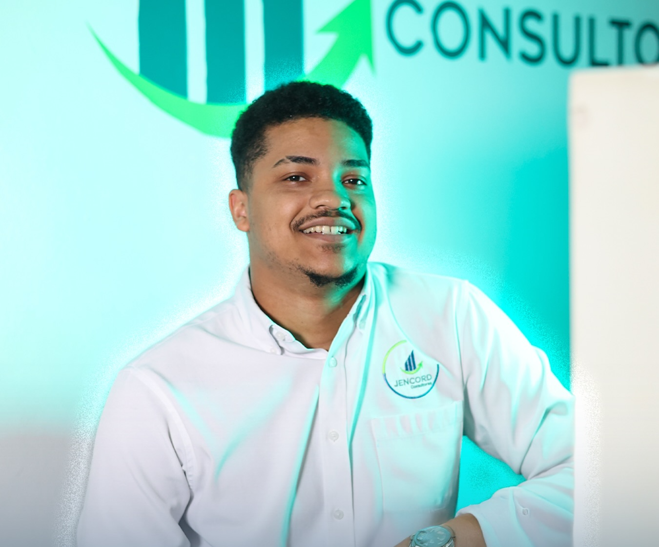 Manos escribiendo en un cuaderno frente a una computadora portátil con gráficos y gráficos en color, en un entorno de oficina.
