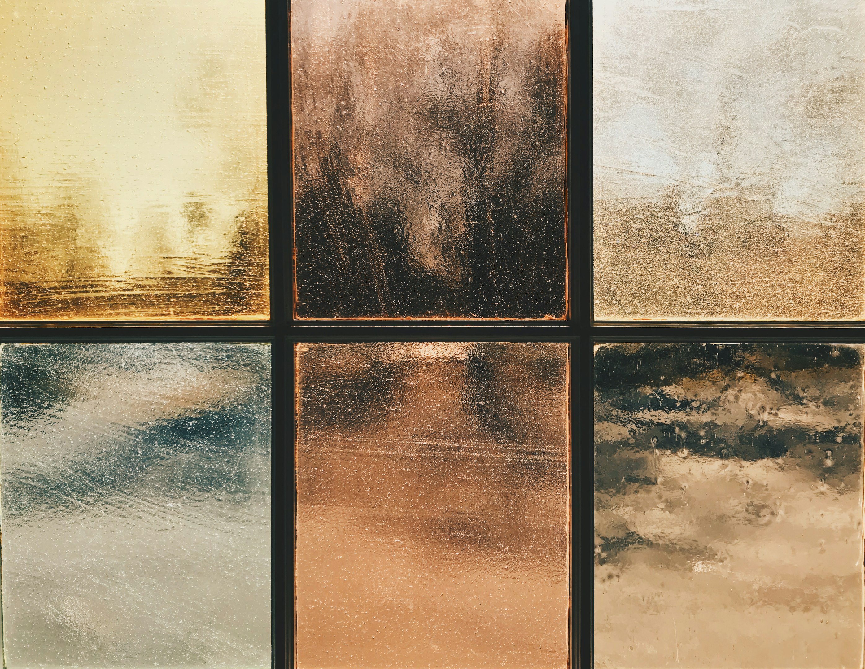 Abstract textured glass panels with warm earth tones and metallic sheen divided into a grid pattern.