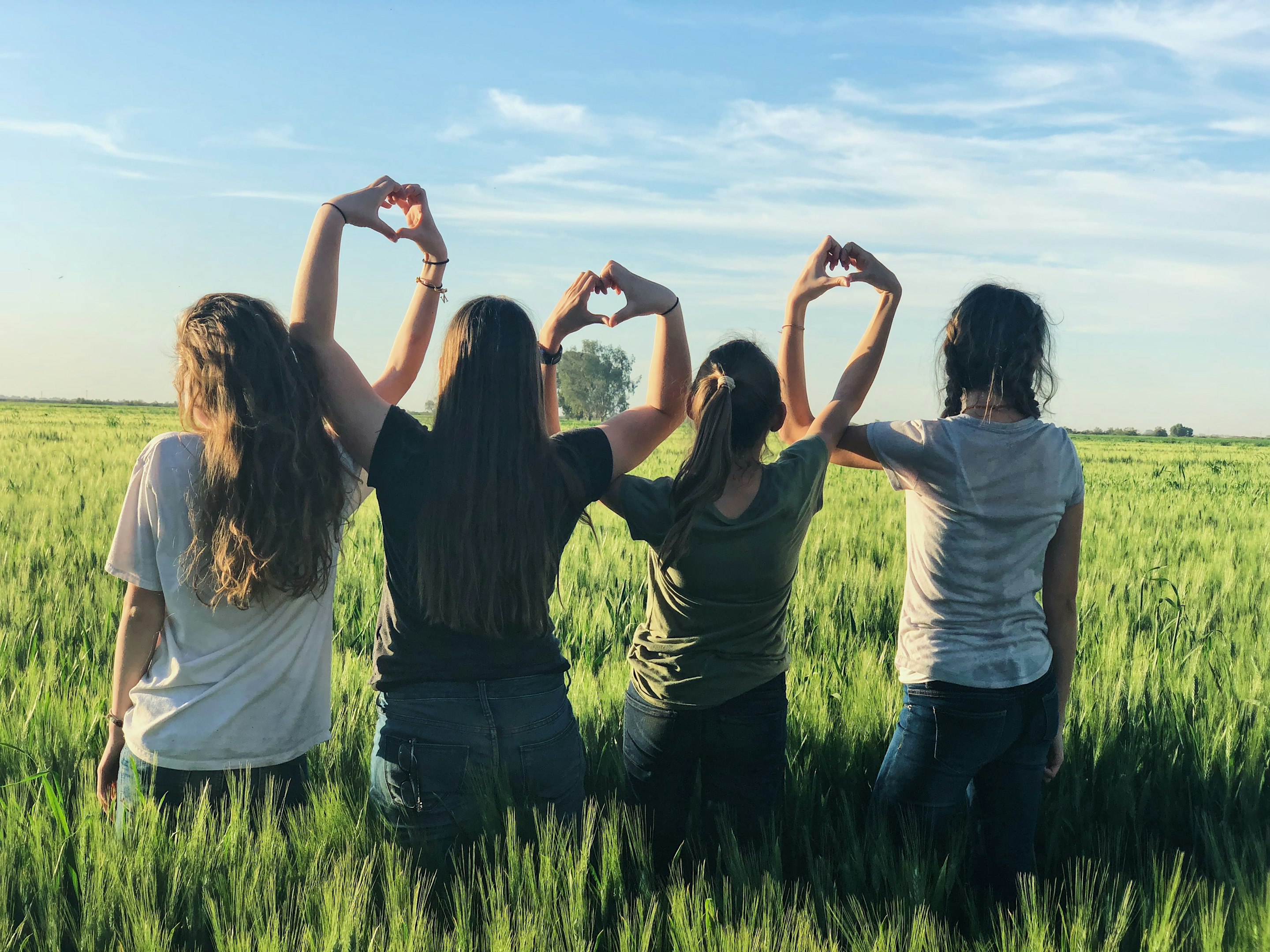 women forming heart gestures during daytime
