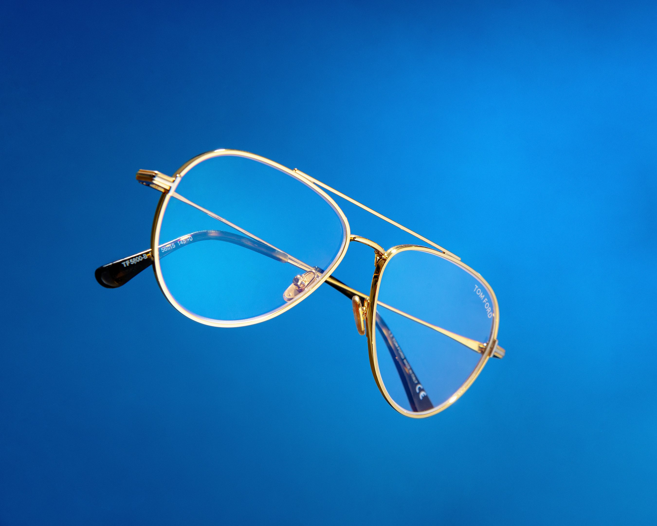 Gafas de sol con montura dorada flotando sobre fondo azul.