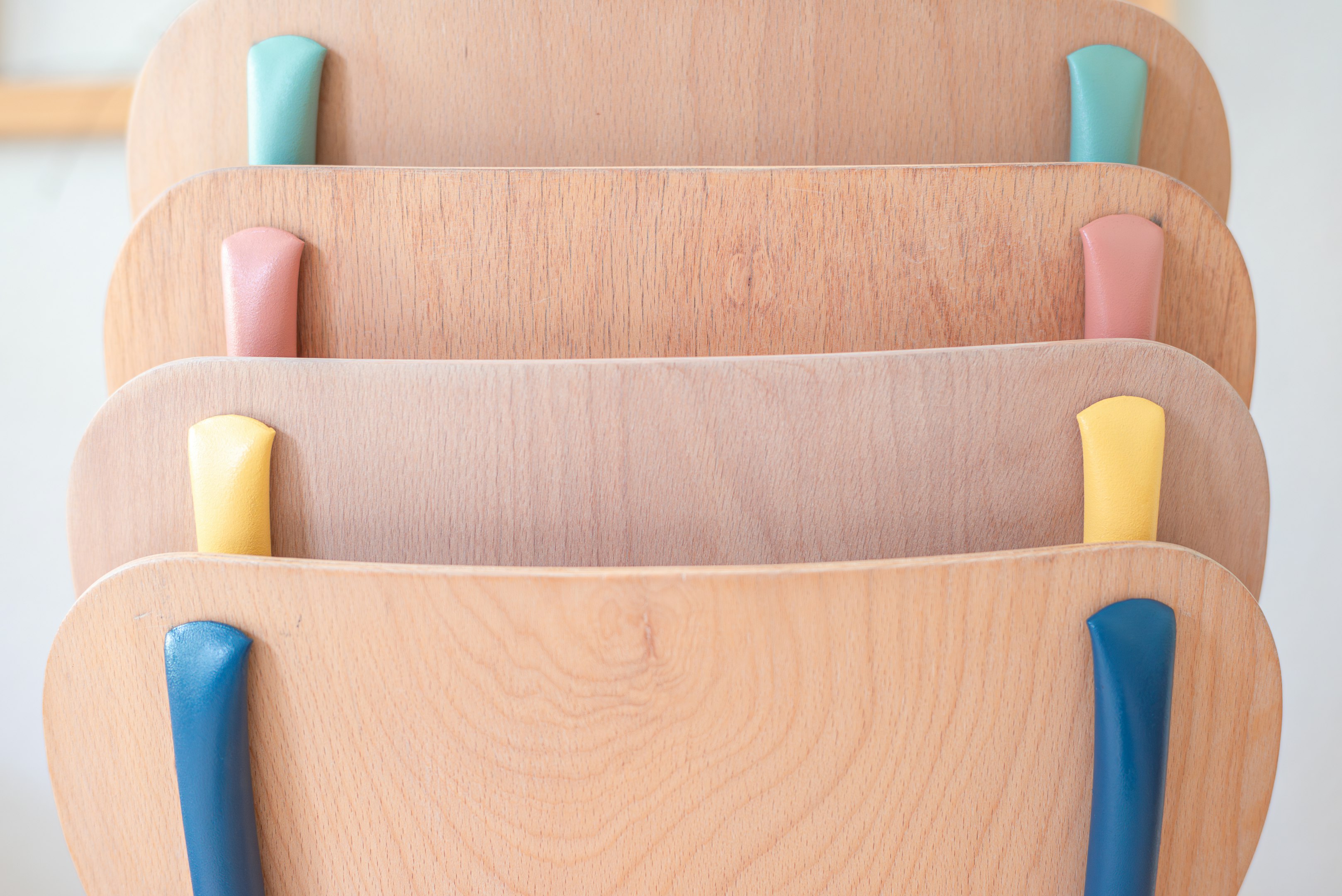 una pila de sillas de madera con asas azules