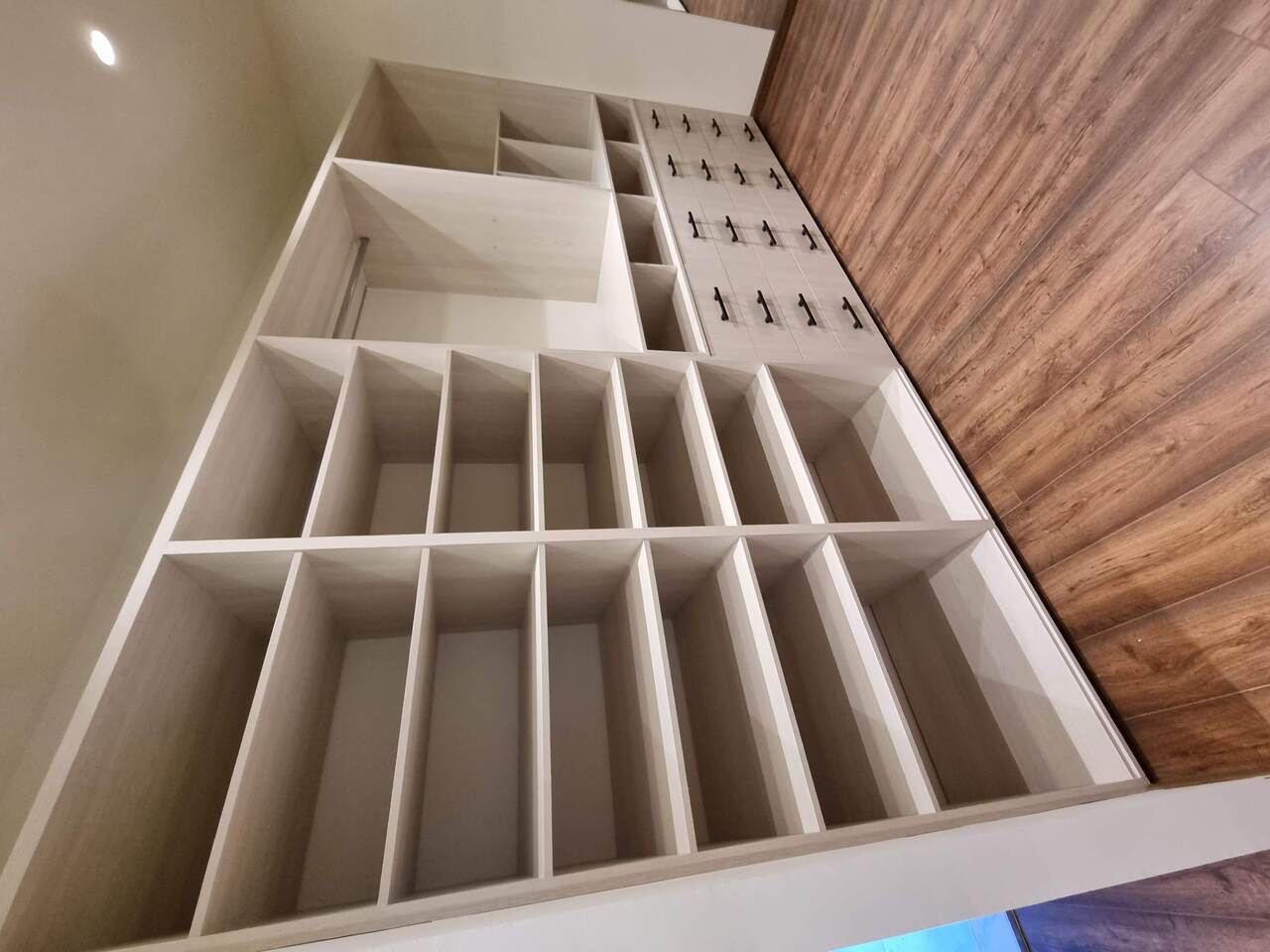 Sala de estar moderna con sofá de cuero claro, pared de ladrillo a la vista, estantería de madera oscura y aire acondicionado.
