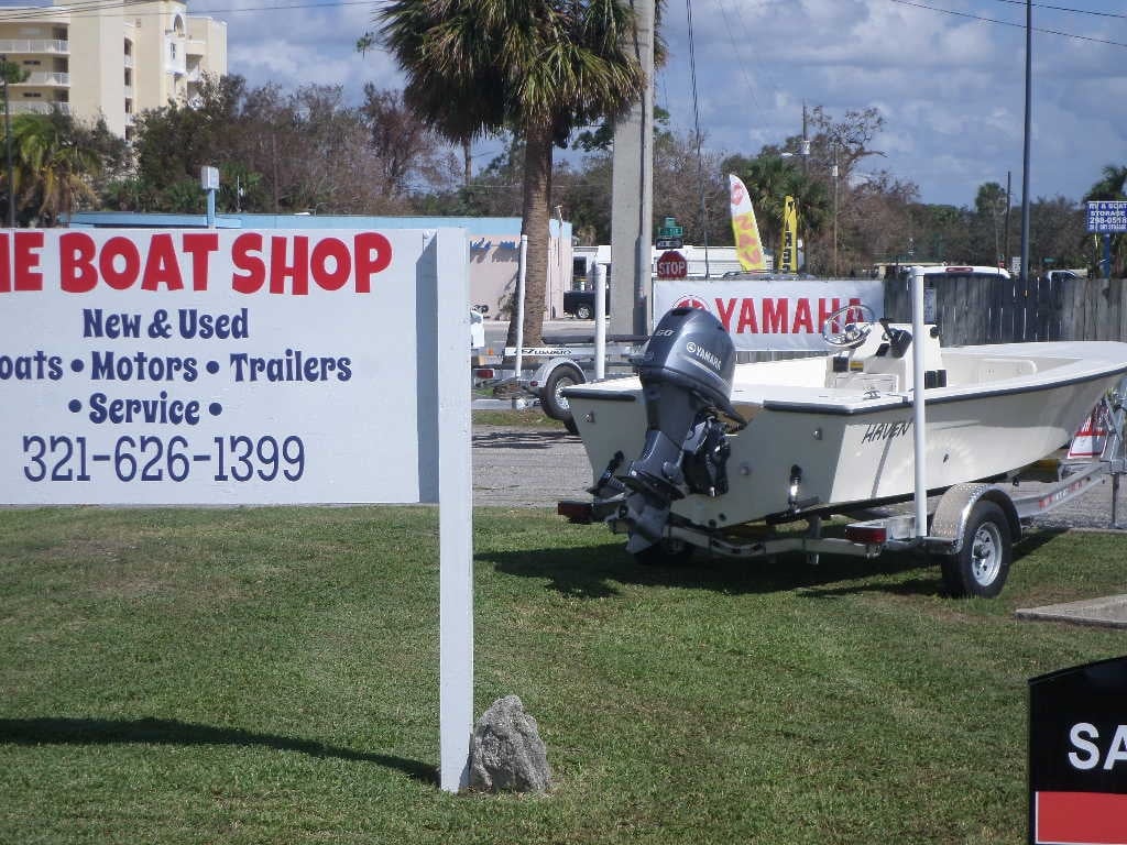 Boat shop display with Yamaha outboard motorboat on trailer and sign for new and used boats, motors, trailers, and service
