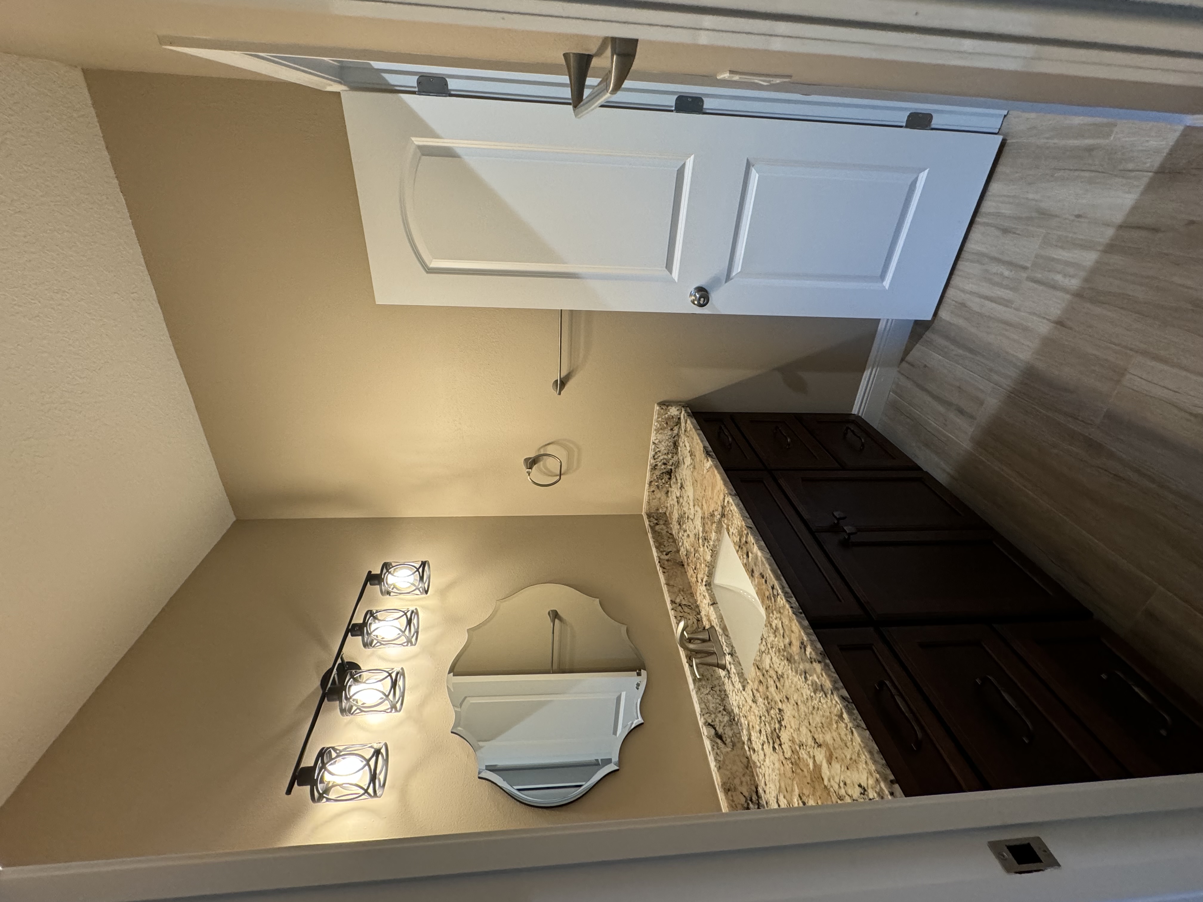 Perfect guest vanity with drawers for extra storage featuring semi-custom maple wood-stained Ginger Snap cabinetry with granite countertop and 4" matching backsplash.