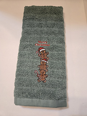 Green hand towel featuring a stack of gingerbread men