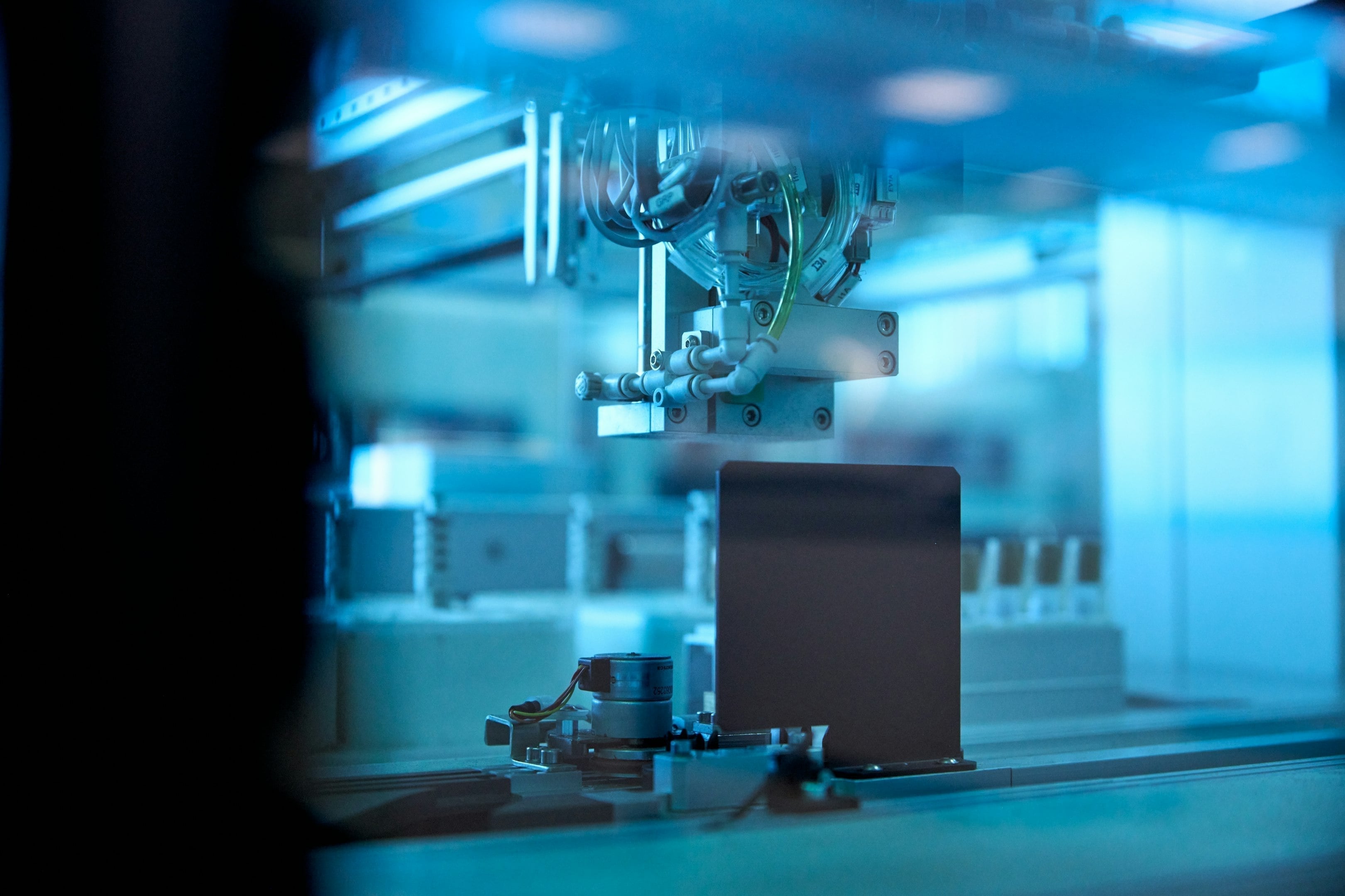 Primer plano de una máquina industrial automatizada en un entorno de fabricación con iluminación azul.