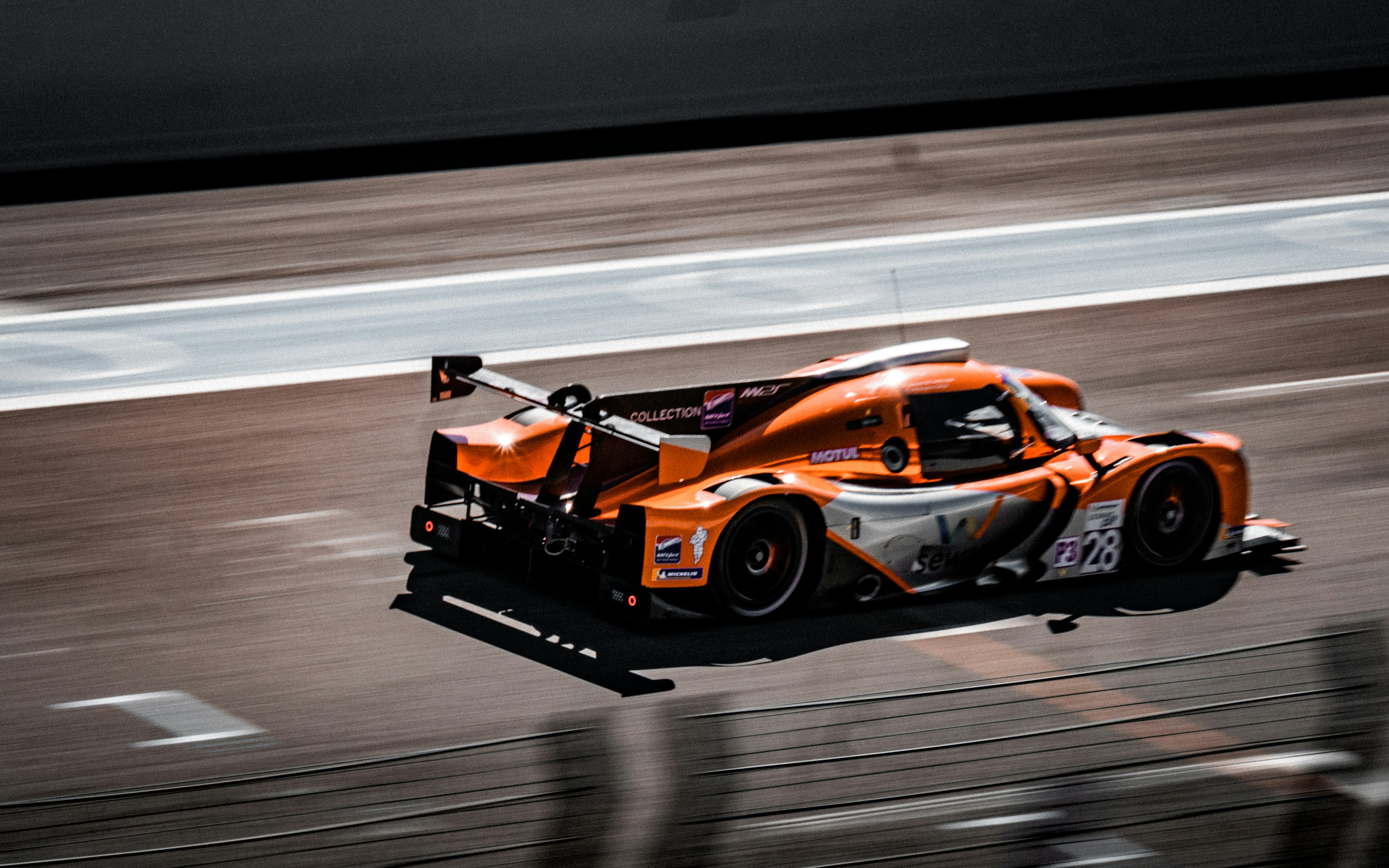 un auto de carreras naranja conduciendo por una pista de carreras