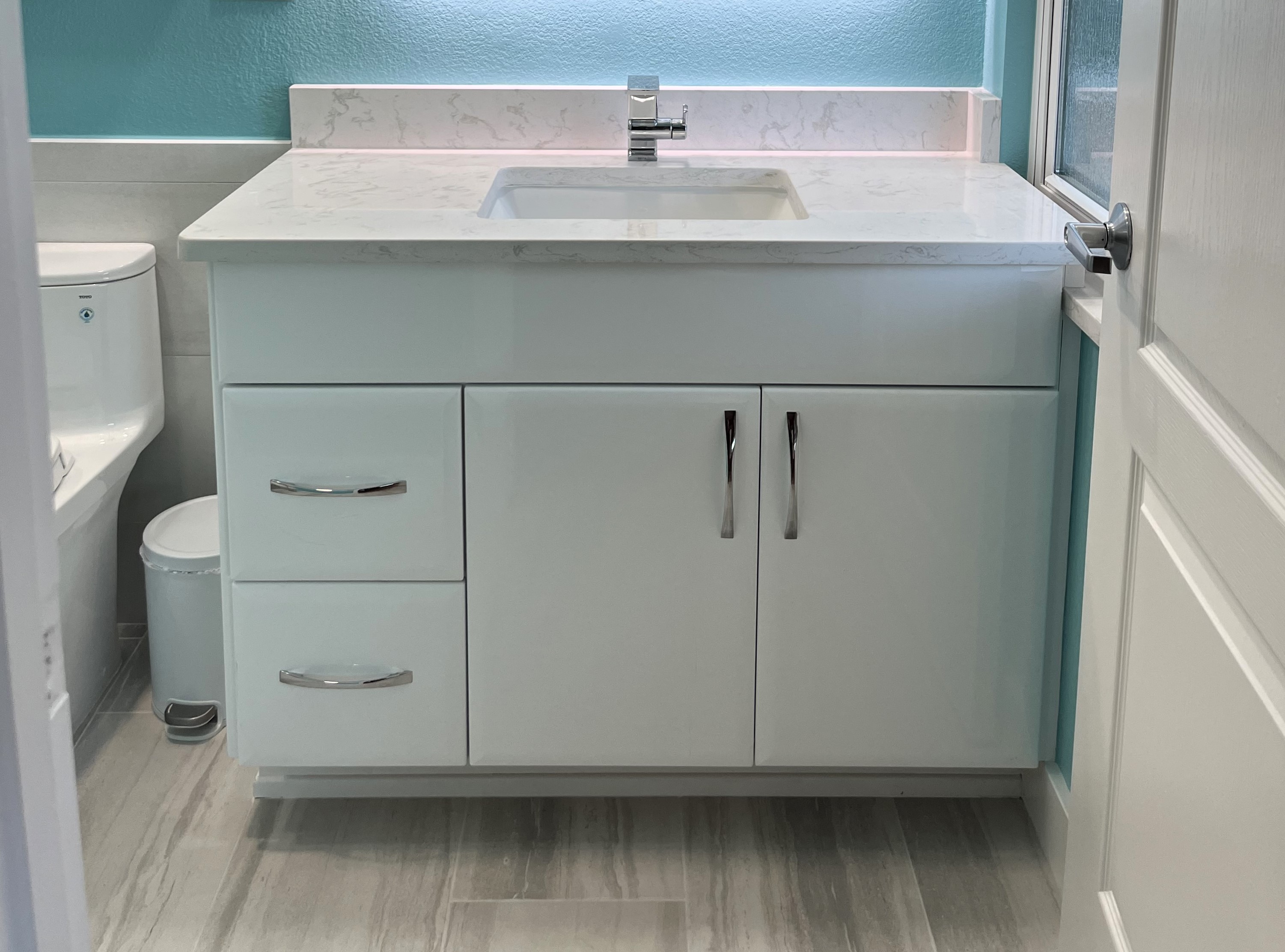 Beautiful white modern vanity with chrome hardware and faucet.