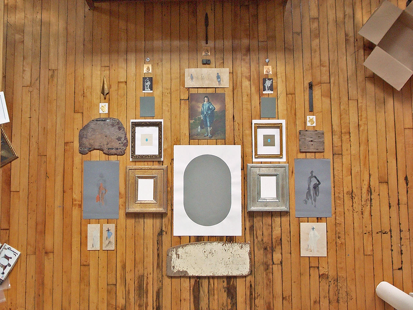 View from above of paintings, drawings and objects arranged on a wood floor.