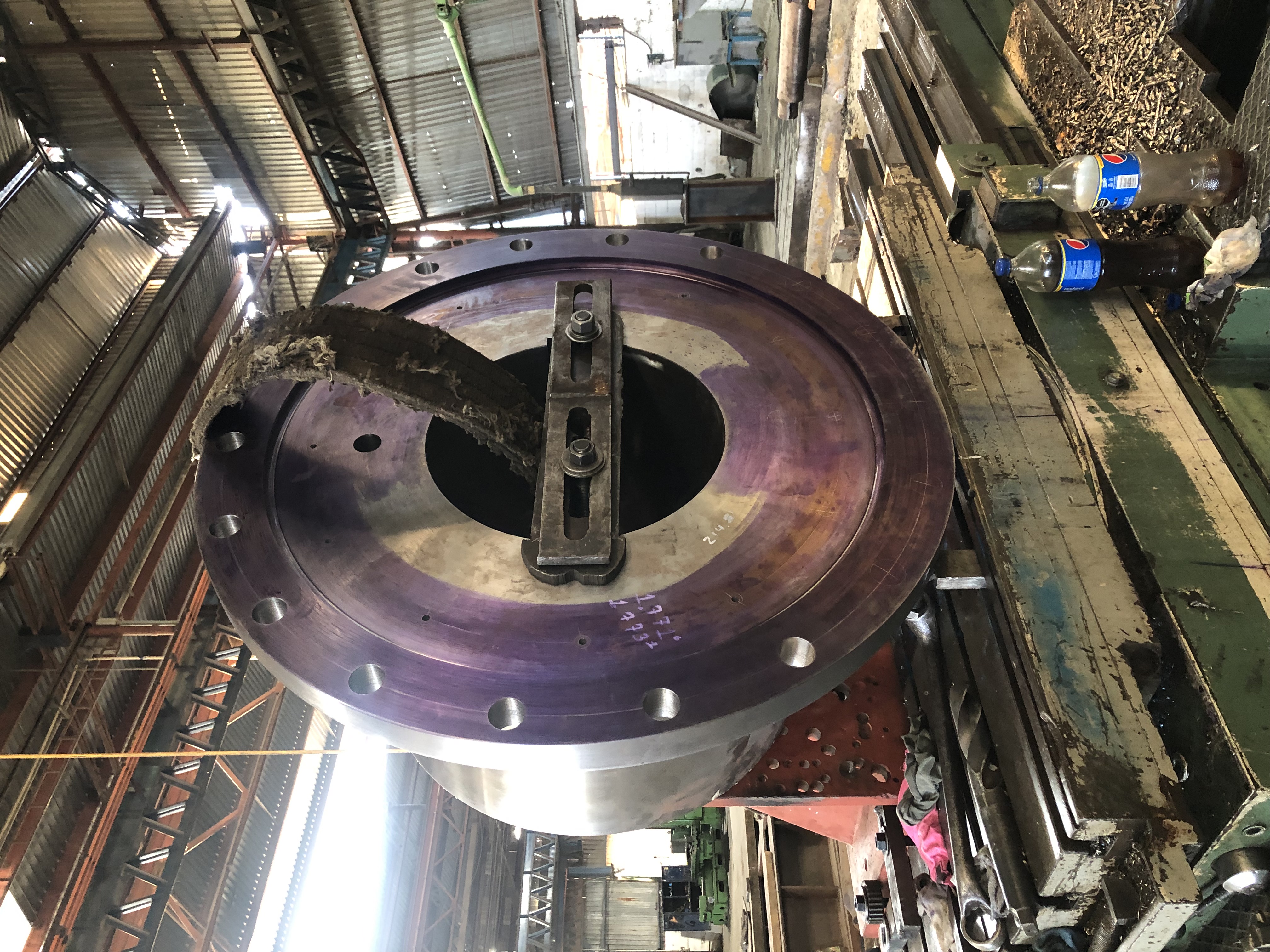 Equipo industrial en taller mecánico con estructura metálica violeta y botellas en primer plano.