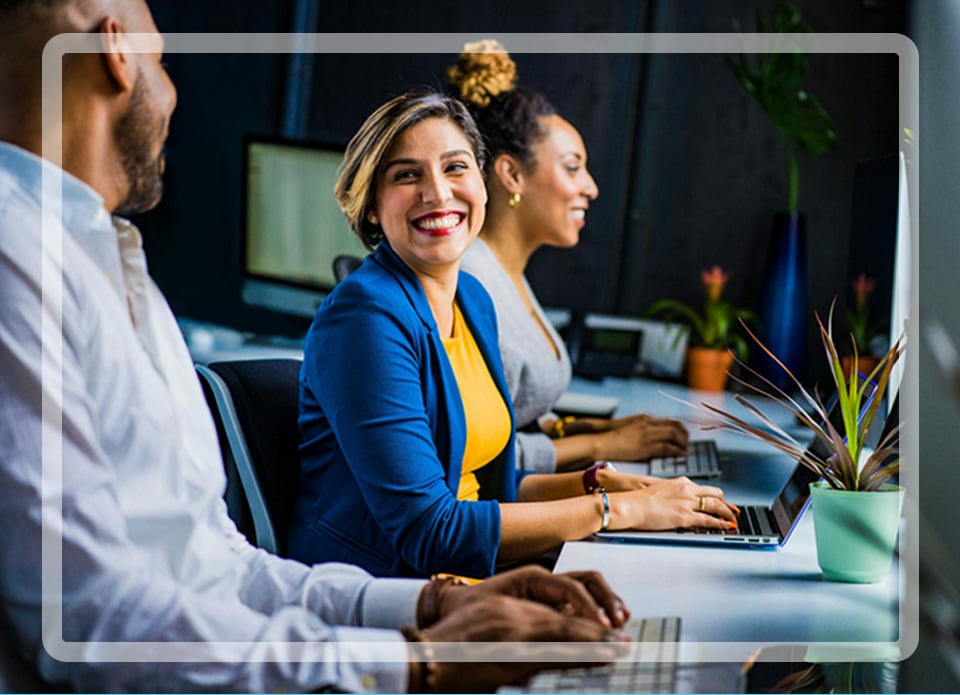 Woman working at a computer with 2 other people next to her working