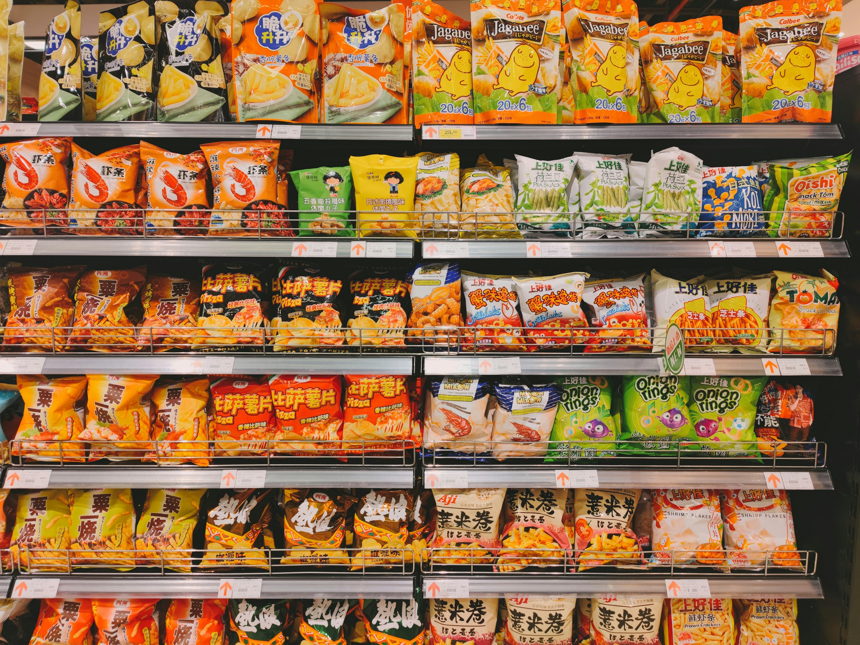 Interior de un supermercado con pasillo de frutas y verduras frescas y personas comprando.