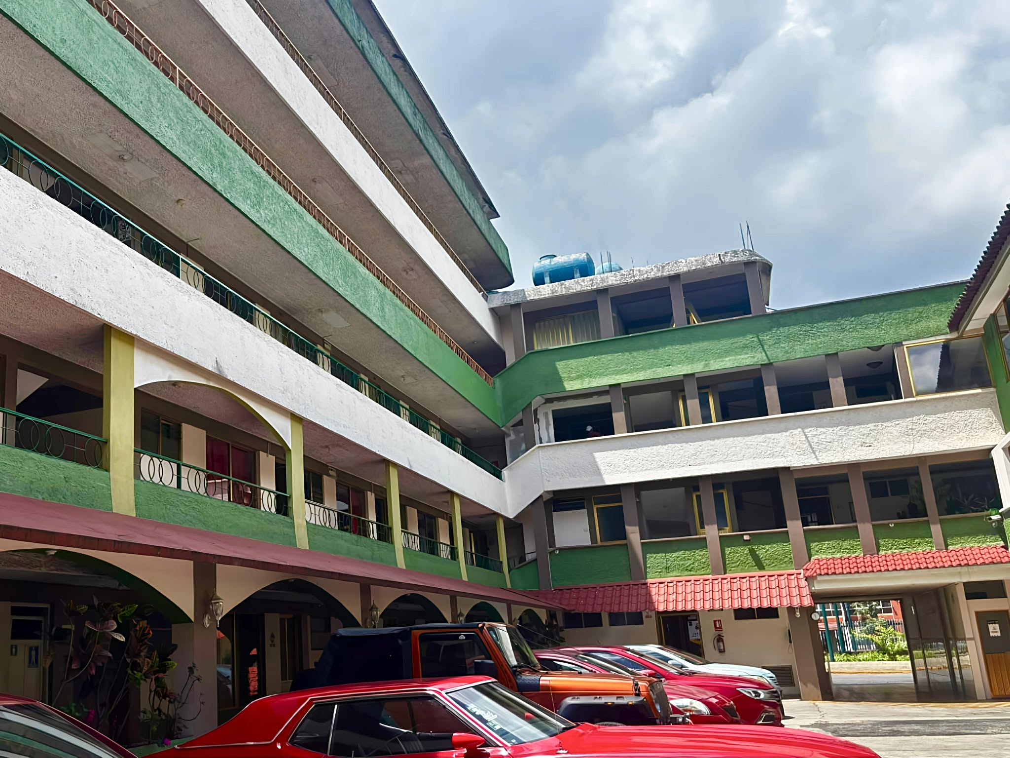 Piscina iluminada al atardecer frente a un moderno edificio de apartamentos con palmeras.