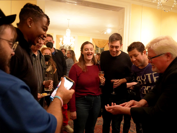 Chuck entertaining a group of people who are smiling and laughing. Chuck entertaining a group of people who are smiling and laughing.