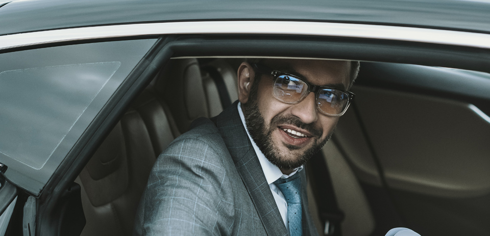 Happy businessman exiting car, reflecting comfortable executive car service