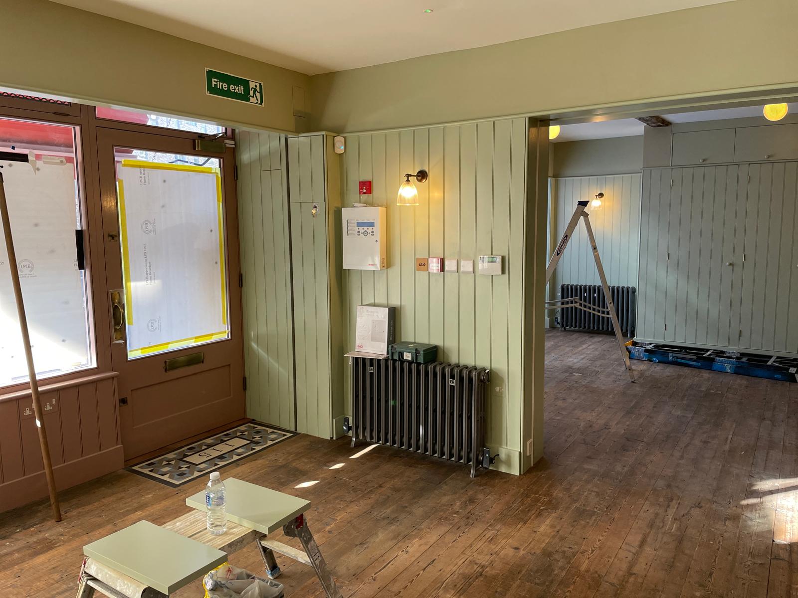 man in black t-shirt and gray pants standing near white wall