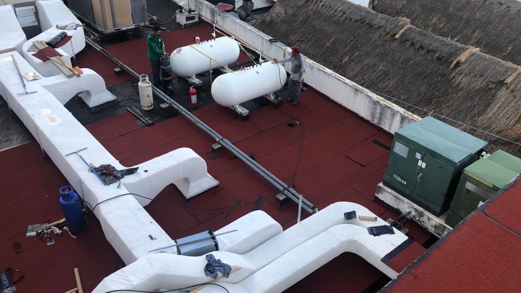 Trabajadores en una azotea con tanques de gas y equipo de aire acondicionado.