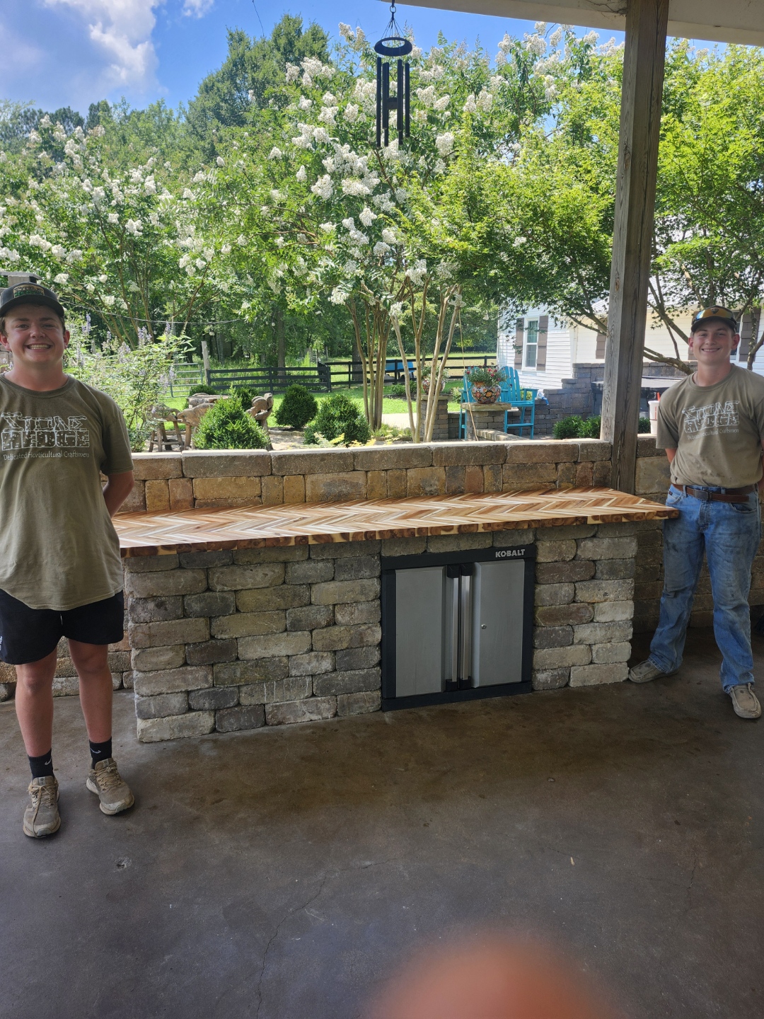 Beautiful garden path with vibrant flowers, lush greenery, and tall trees on a sunny day.