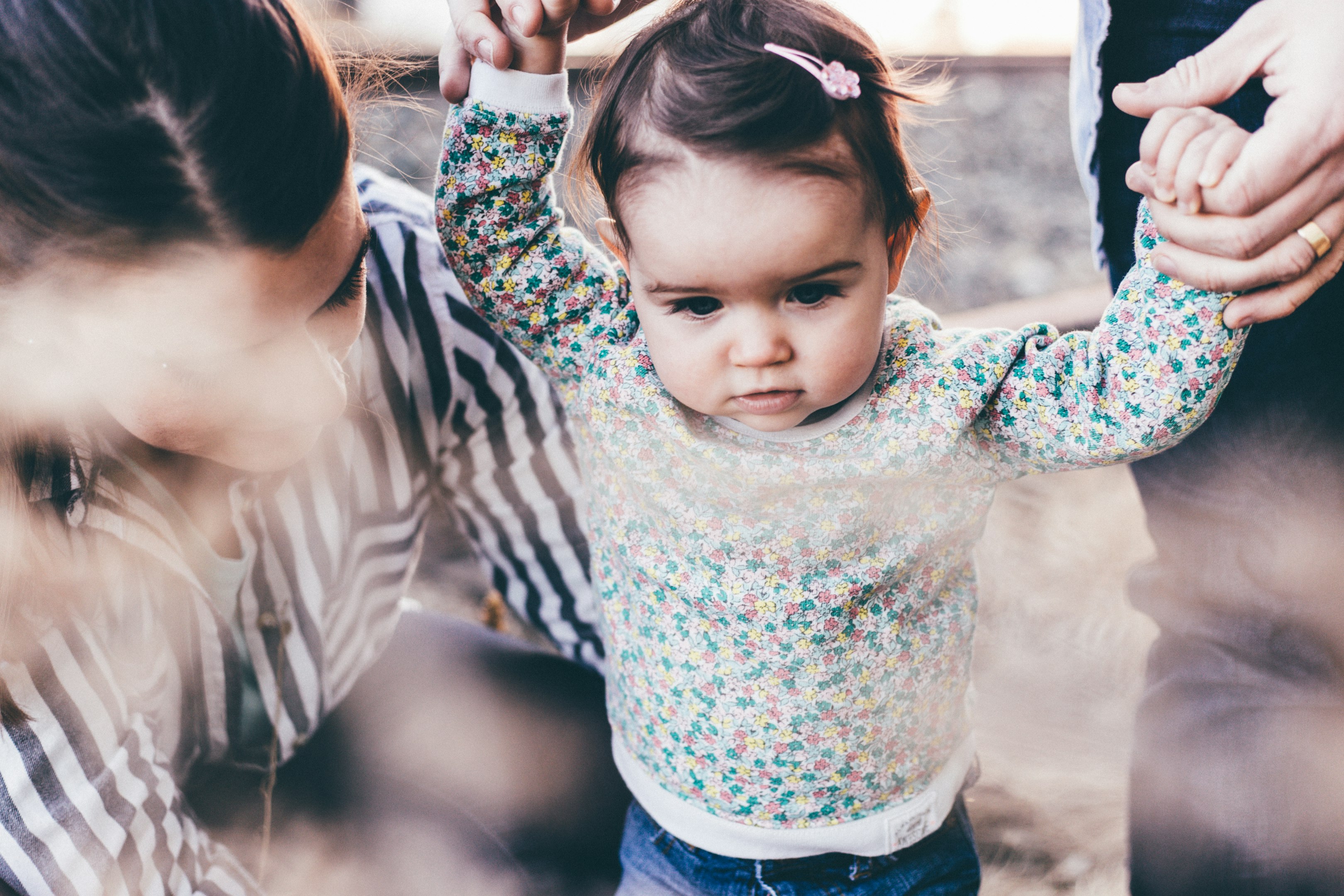mujer sosteniendo a una niña mientras aprende a caminar durante el día