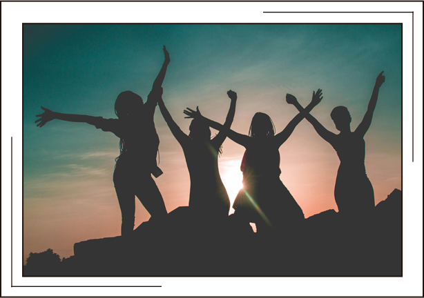Outline of four people with their arms up in the air, in front of a sunset