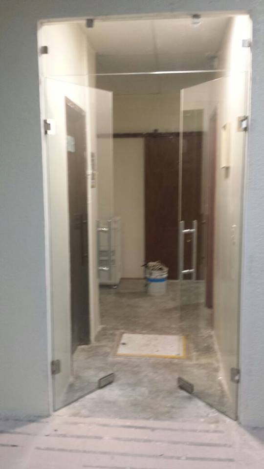 Cancel templado claro de 9mm con dos puertas abatibles, jaladera y herrajes de acero inoxidable.