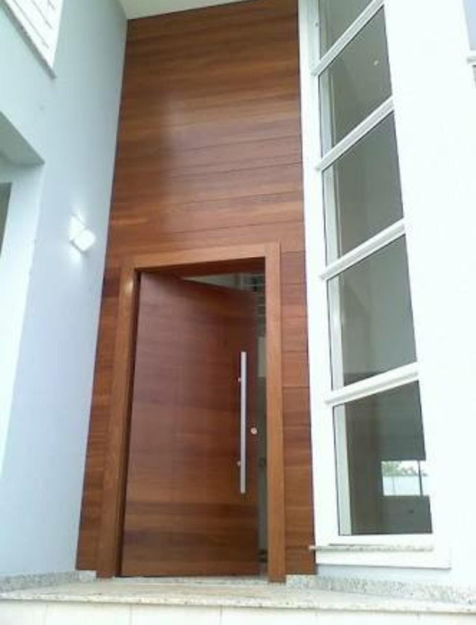 Porta 701 - Porta de madeira, com painel em madeira e sistema de abertura pivotante.